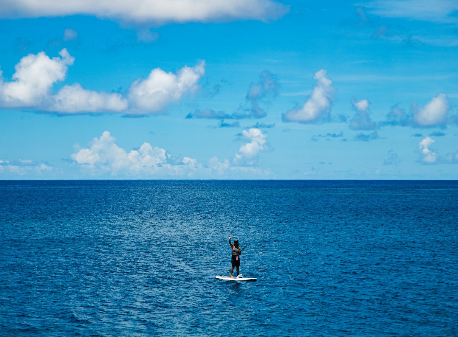 Person steht auf einem Surfbrett im blauen Ozean