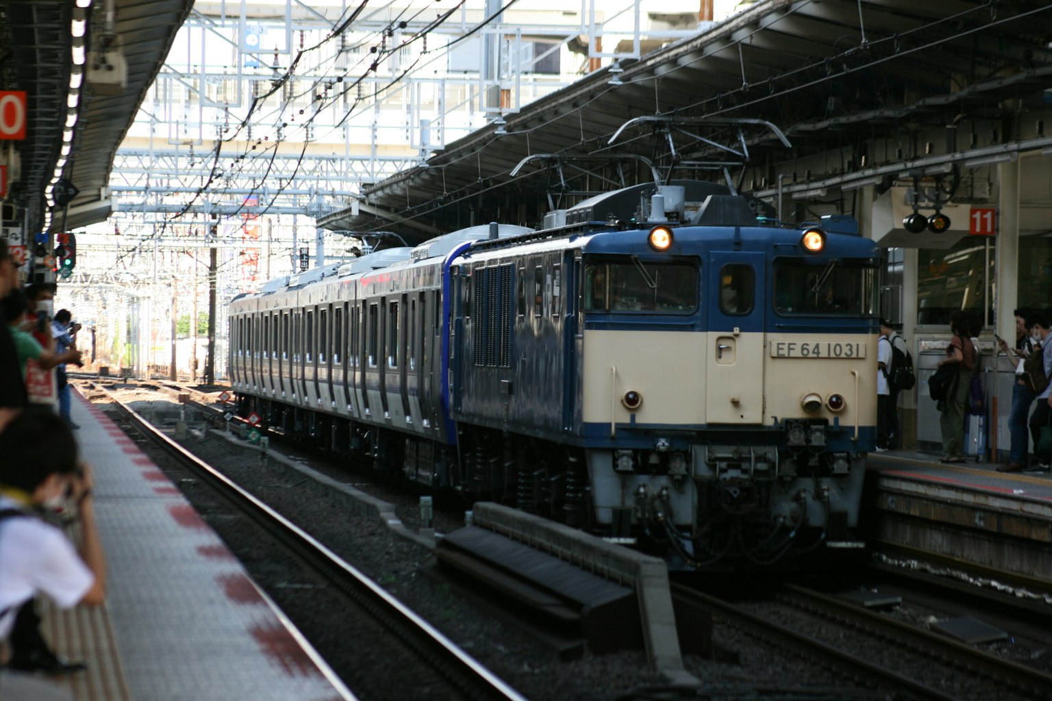 Kereta biru tiba di stasiun dengan struktur yang terlihat