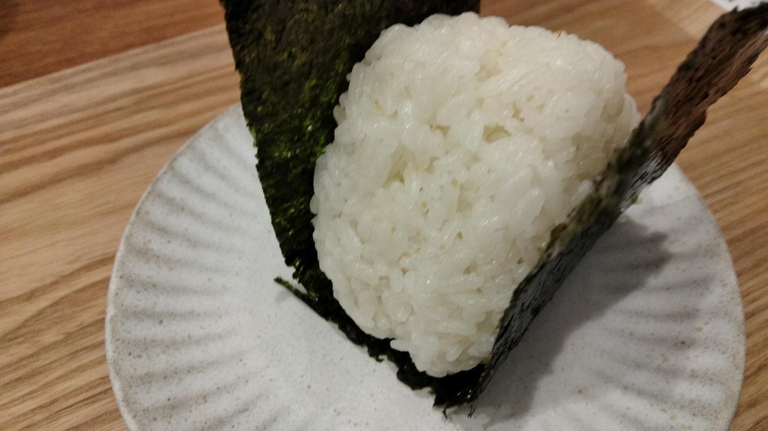 Un onigiri enveloppé dans une algue sur une assiette blanche