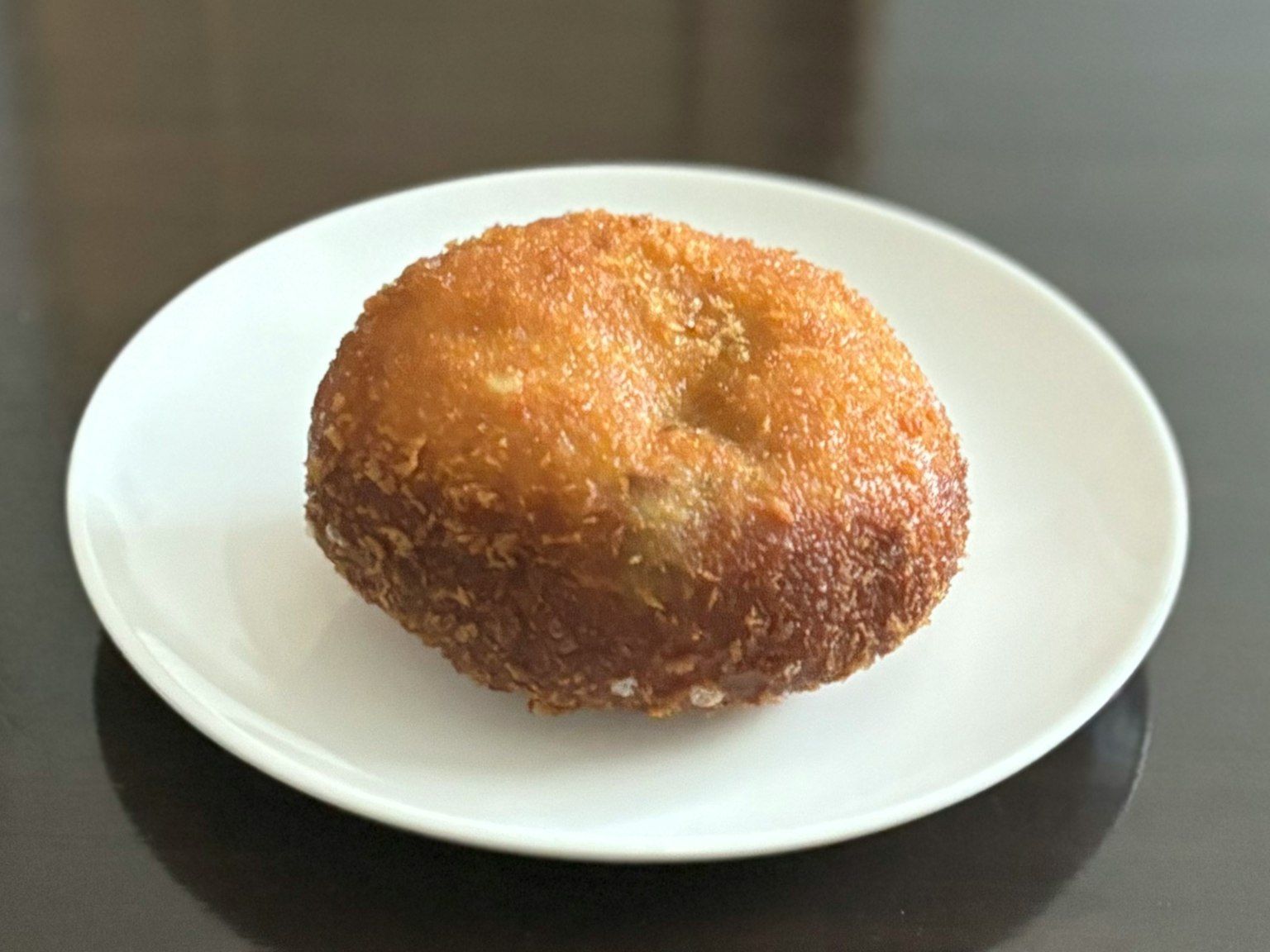 Pâtisserie frite en forme de beignet sur une assiette blanche