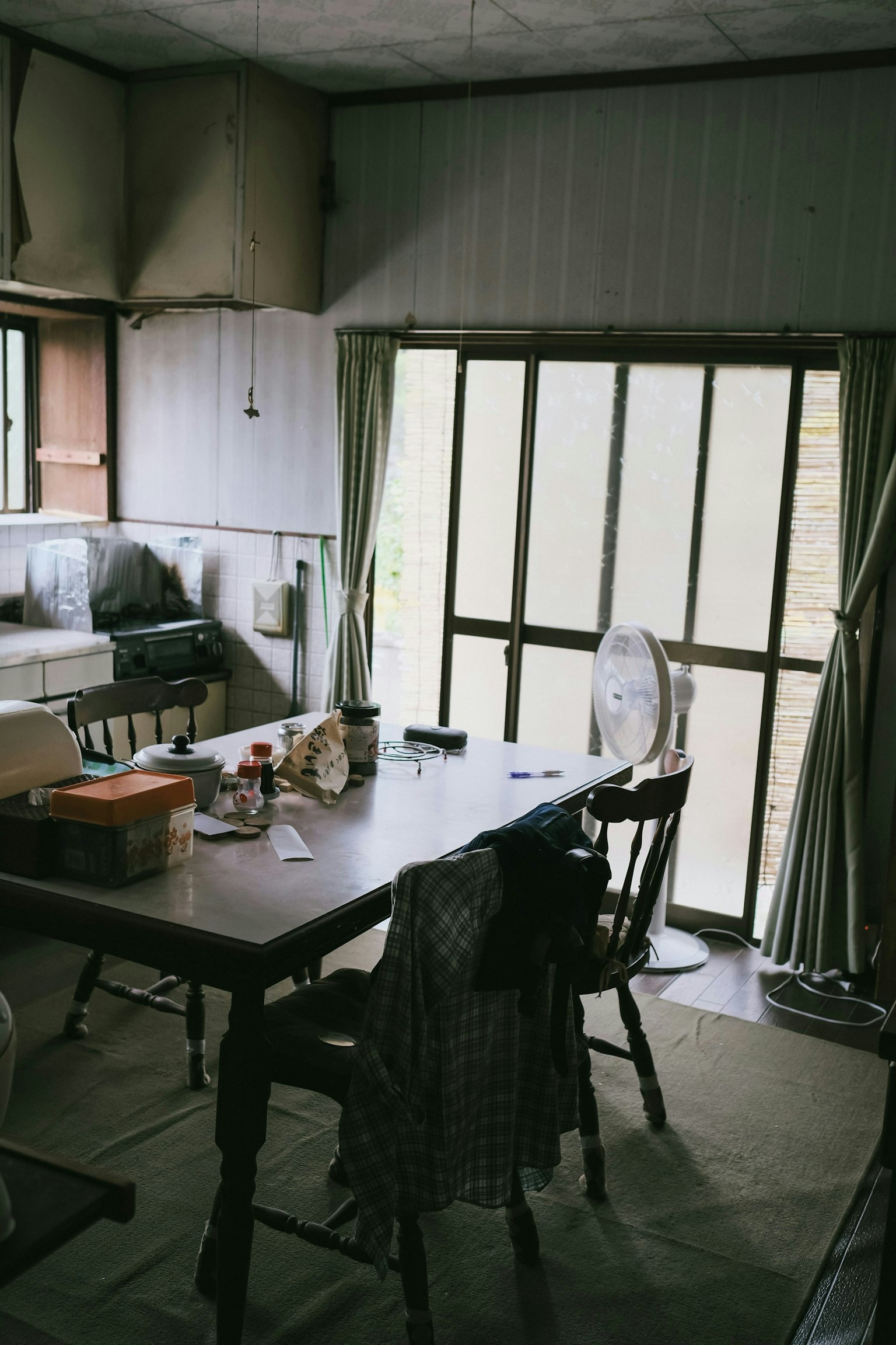 Interior ruang makan sederhana dengan meja dan kursi cahaya alami masuk melalui jendela