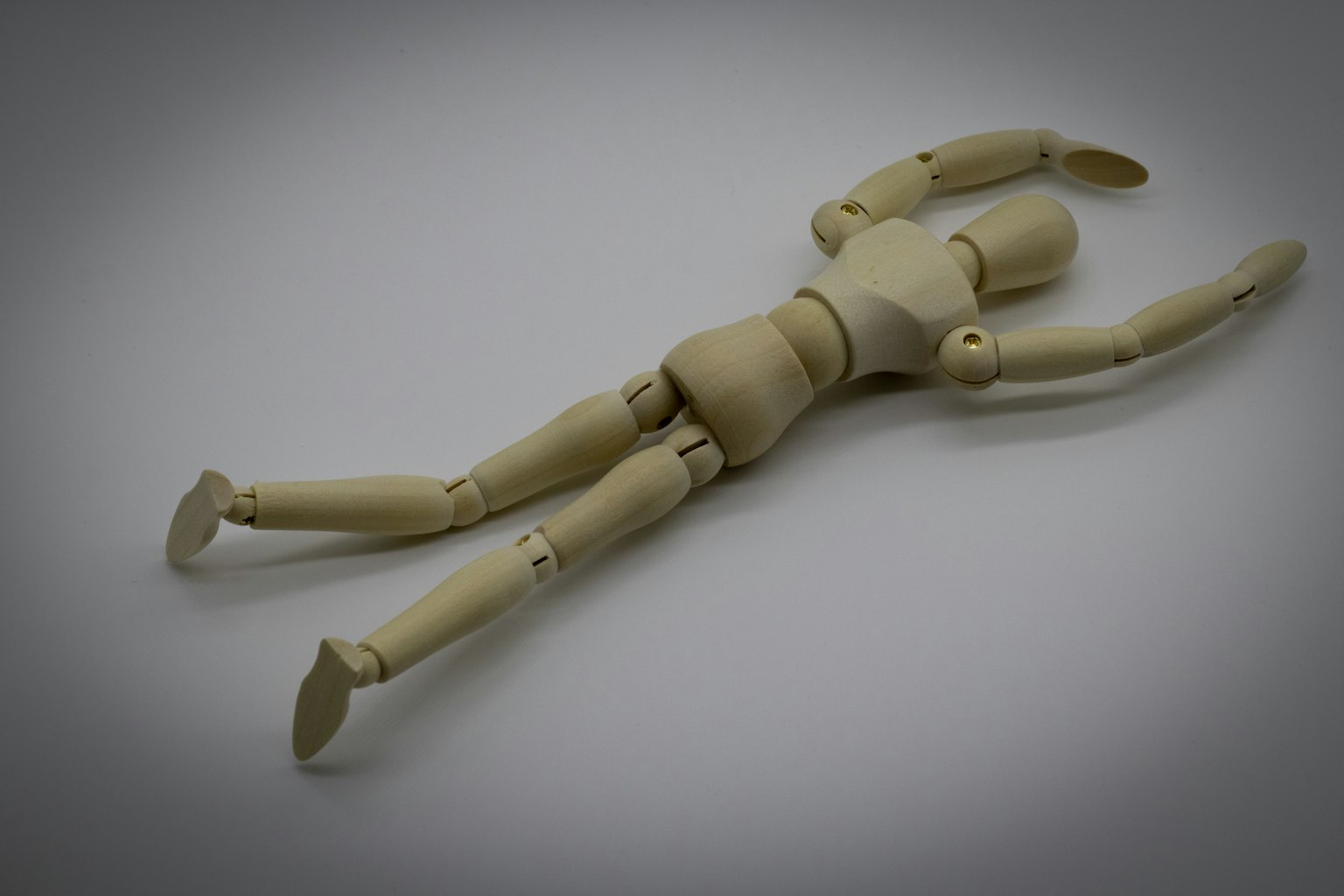 A wooden mannequin lying down in a relaxed pose
