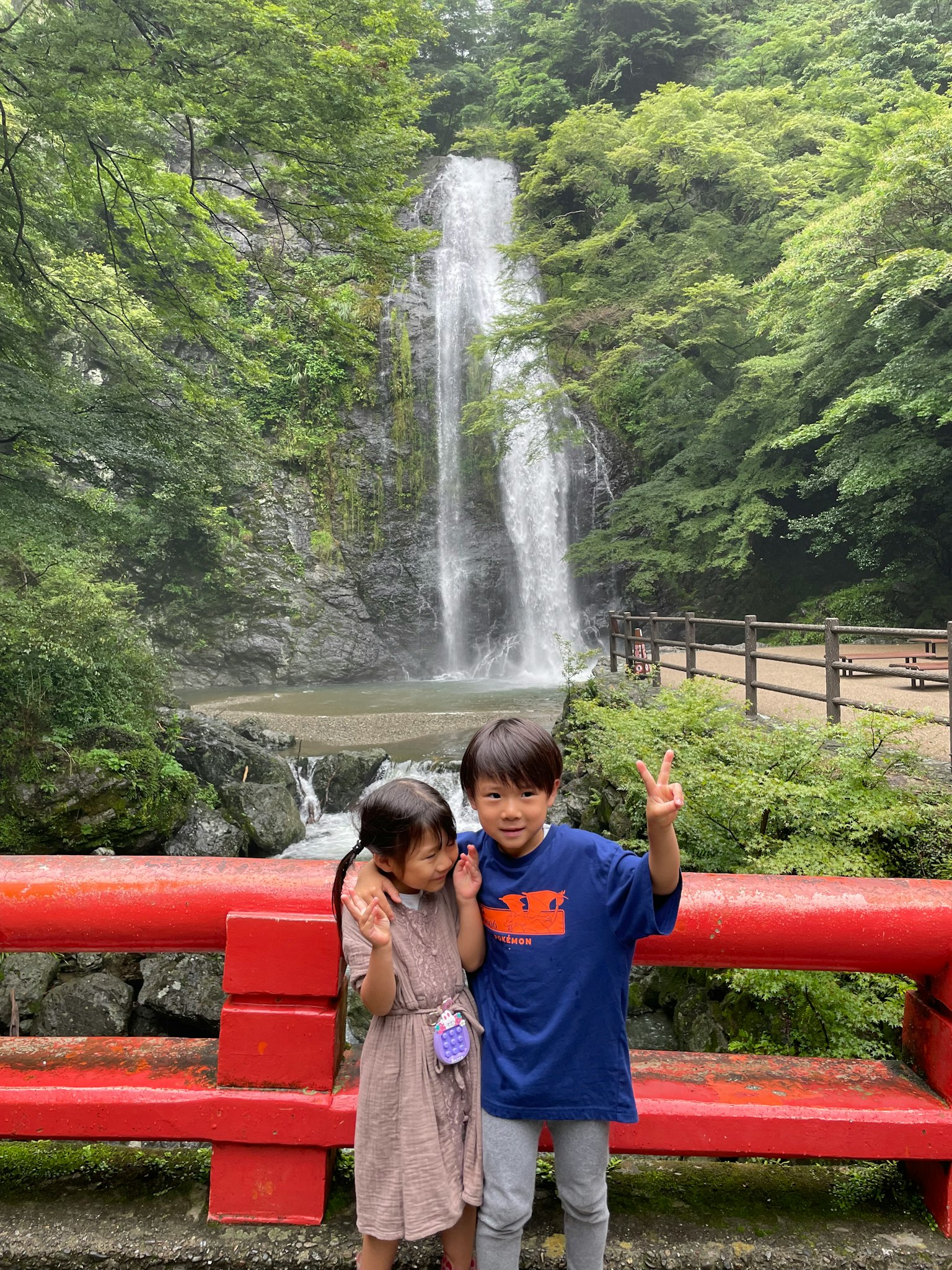 Enfants posant devant une cascade avec un pont rouge