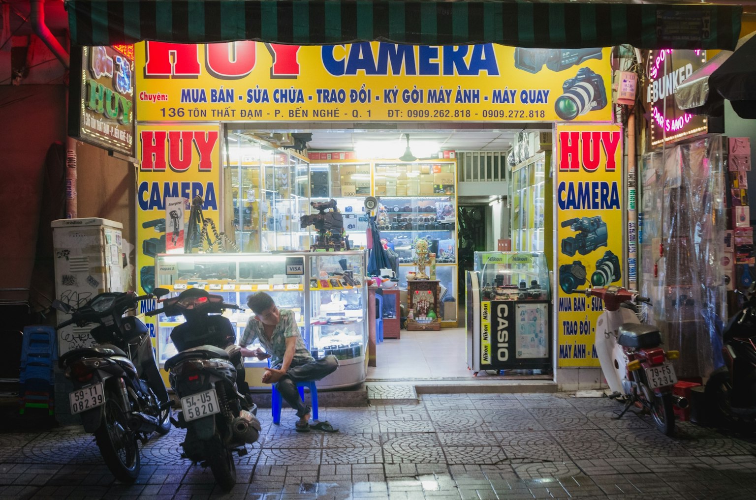 相机店外观明亮的黄色招牌展示产品顾客坐在外面