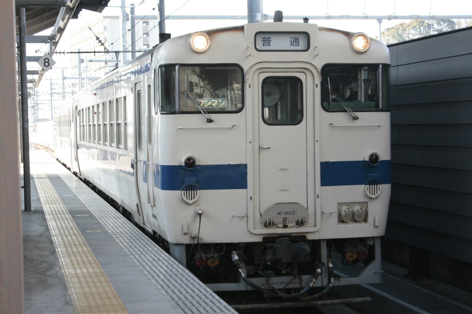 Weißer und blauer Zug hält am Bahnhof