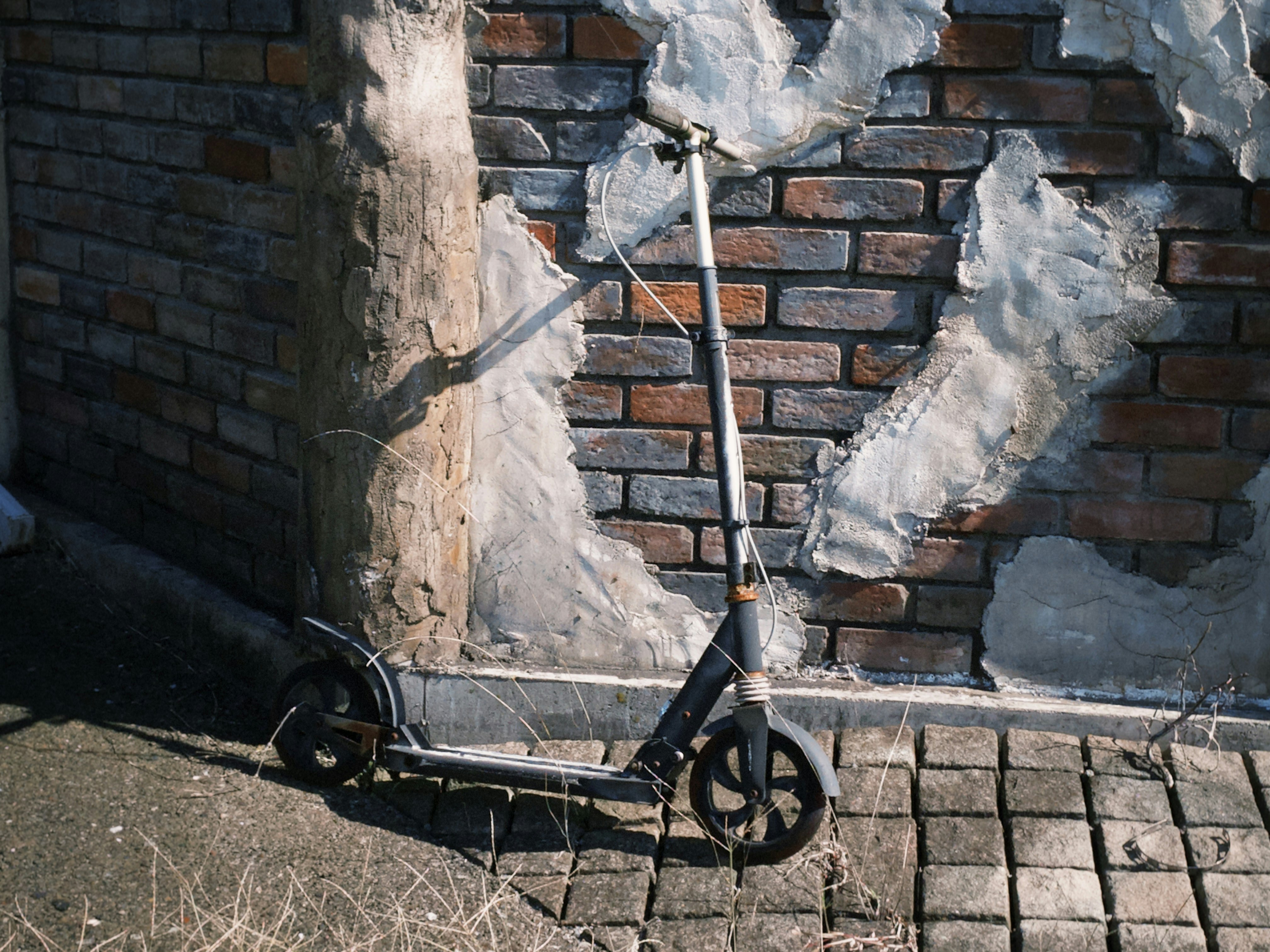 レンガ壁の前に置かれた折りたたみ自転車と配管
