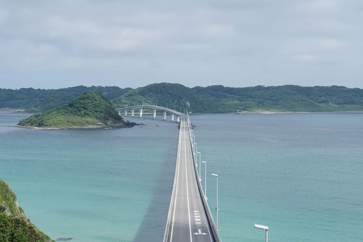Una vista escénica de un puente que se extiende sobre agua azul con una isla al fondo
