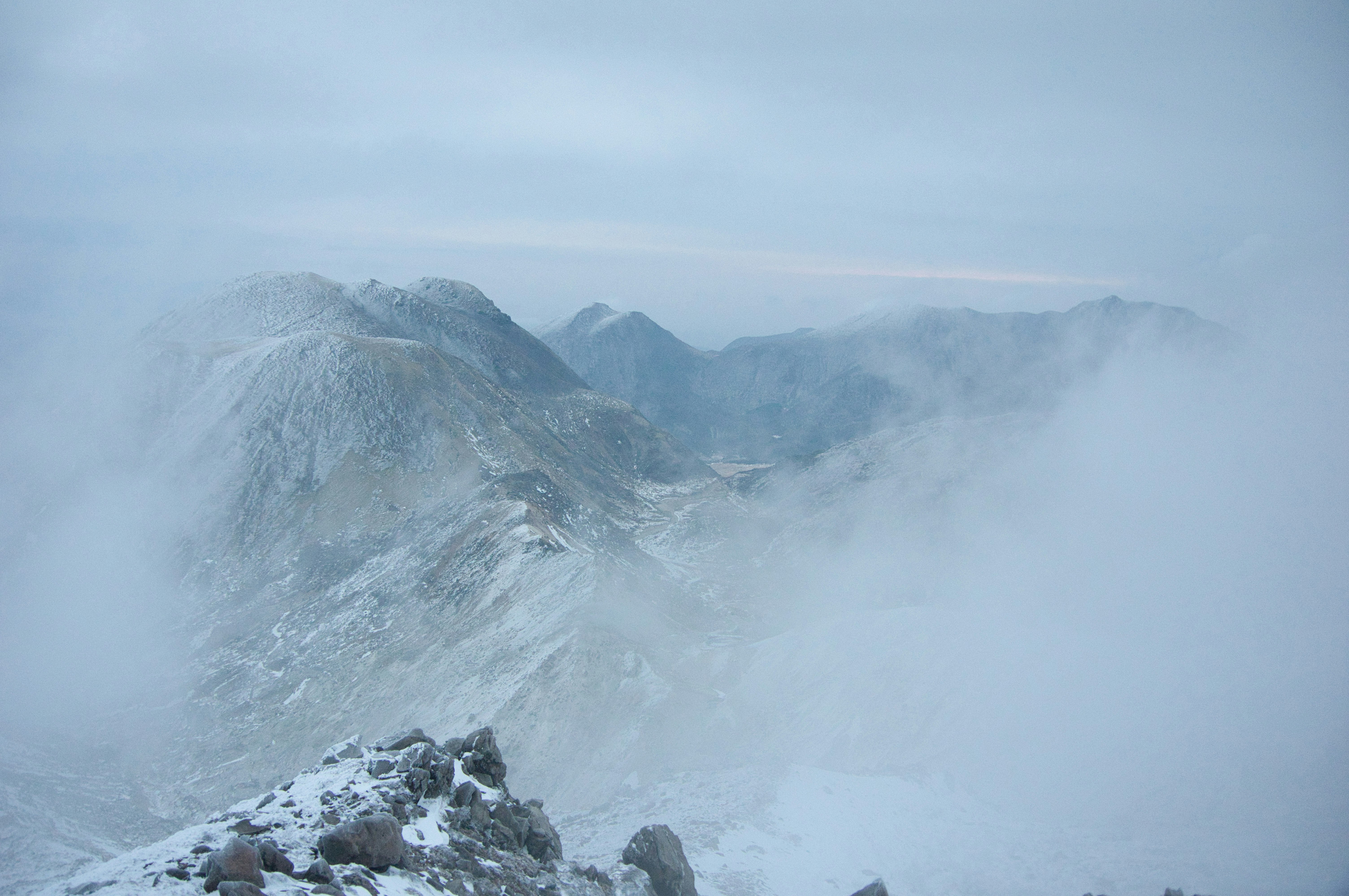ガスに包まれた雪の山頂と雲の夜明け