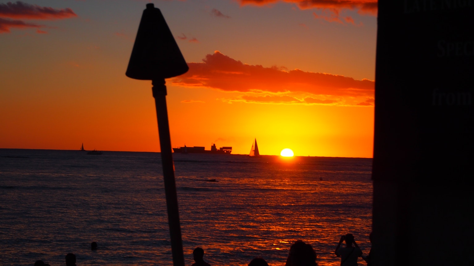 Silhouette di una barca e persone contro un vibrante tramonto sull'oceano