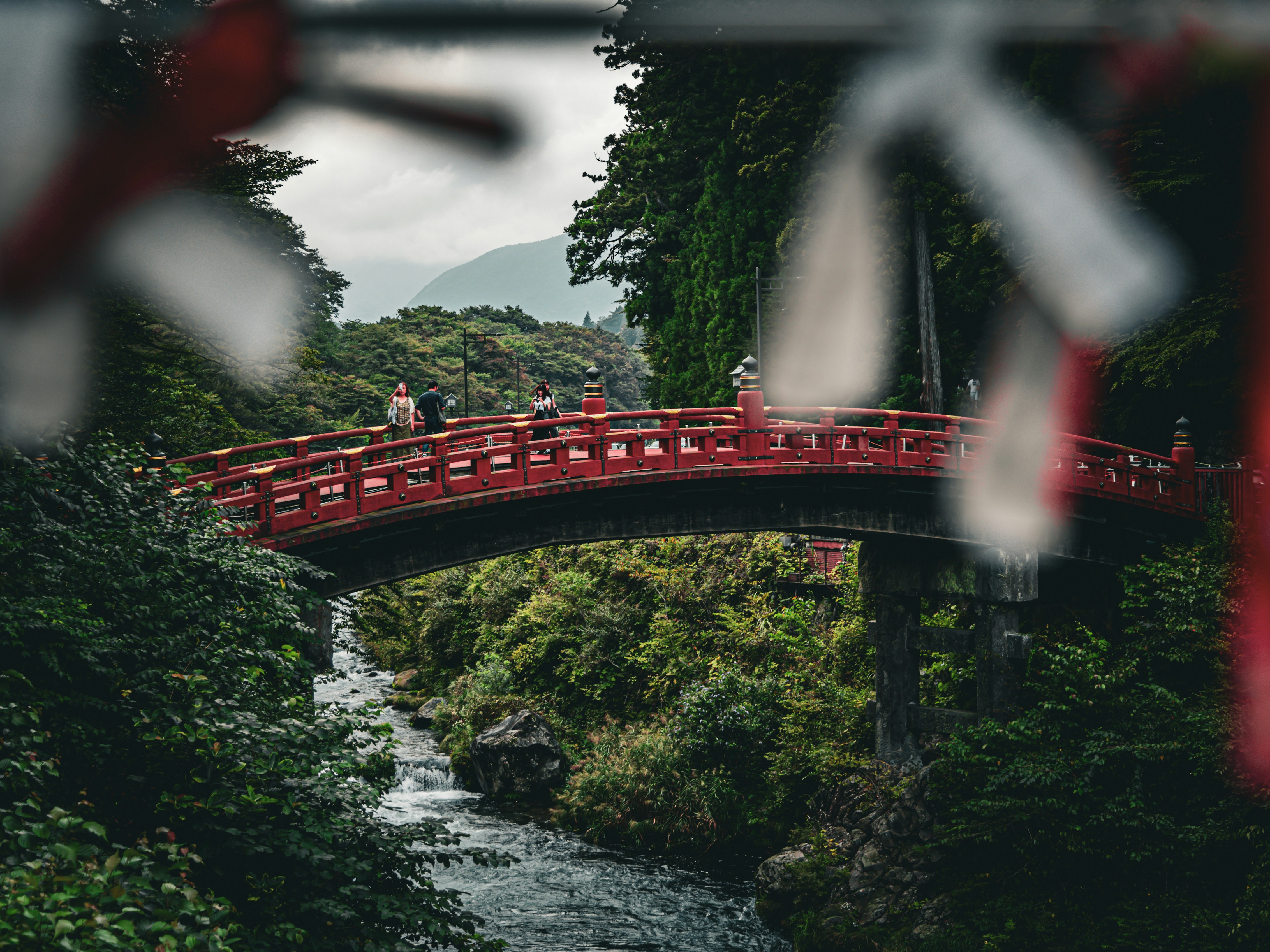 Pemandangan lengkung Jembatan Shinkyo merah menyala di atas sungai