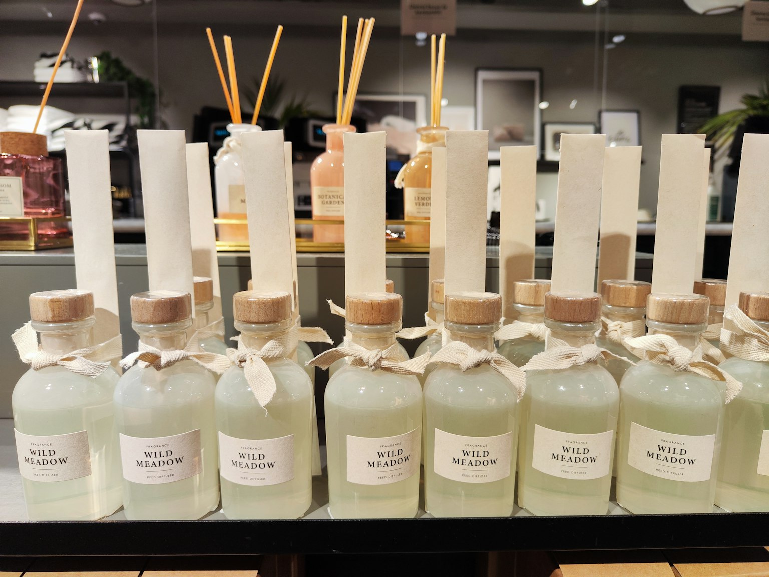 Display of glass bottles with green liquid and white labels arranged on a shelf