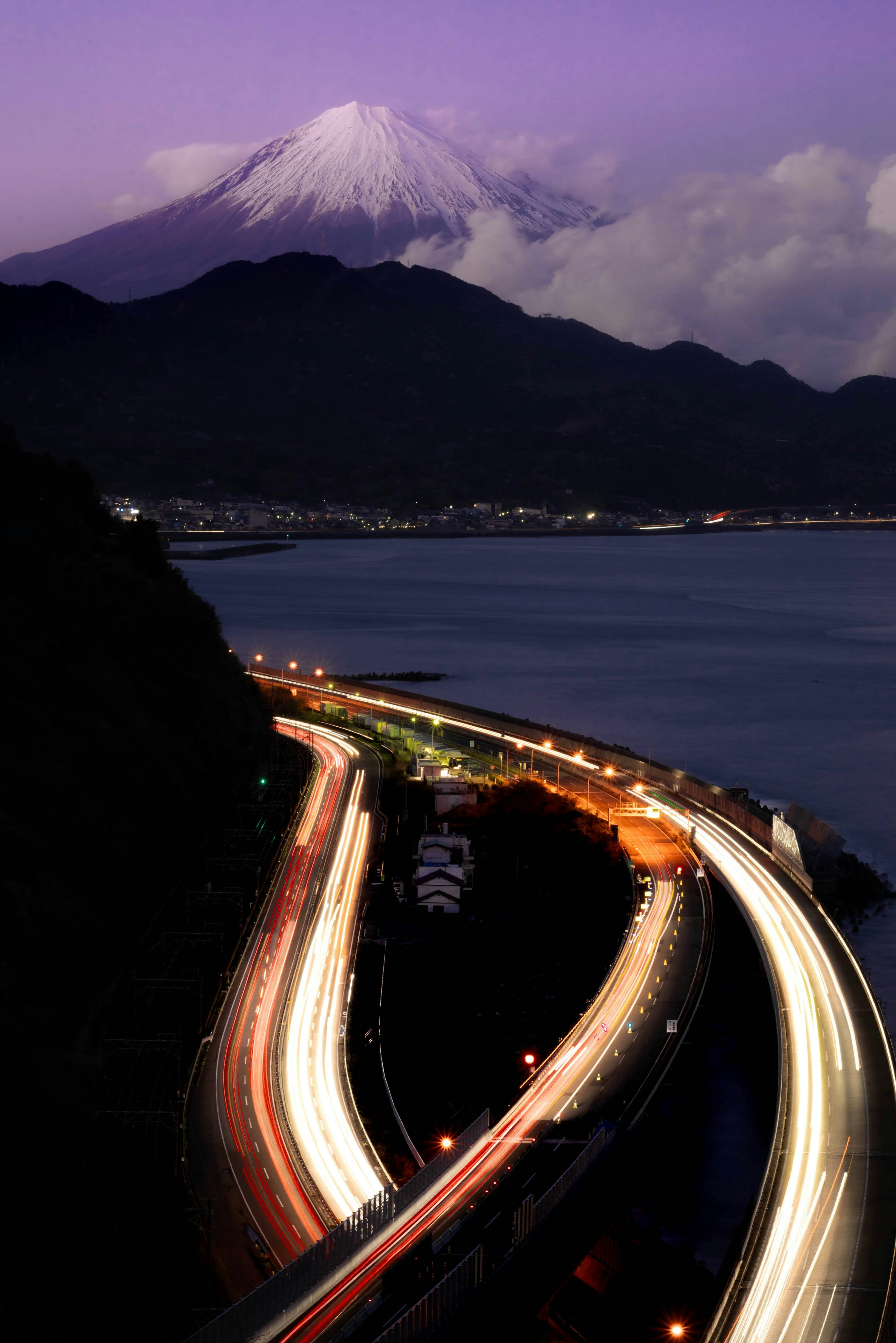 春夜の薩埵峠から望む富士山と海沿いの夜景の道路