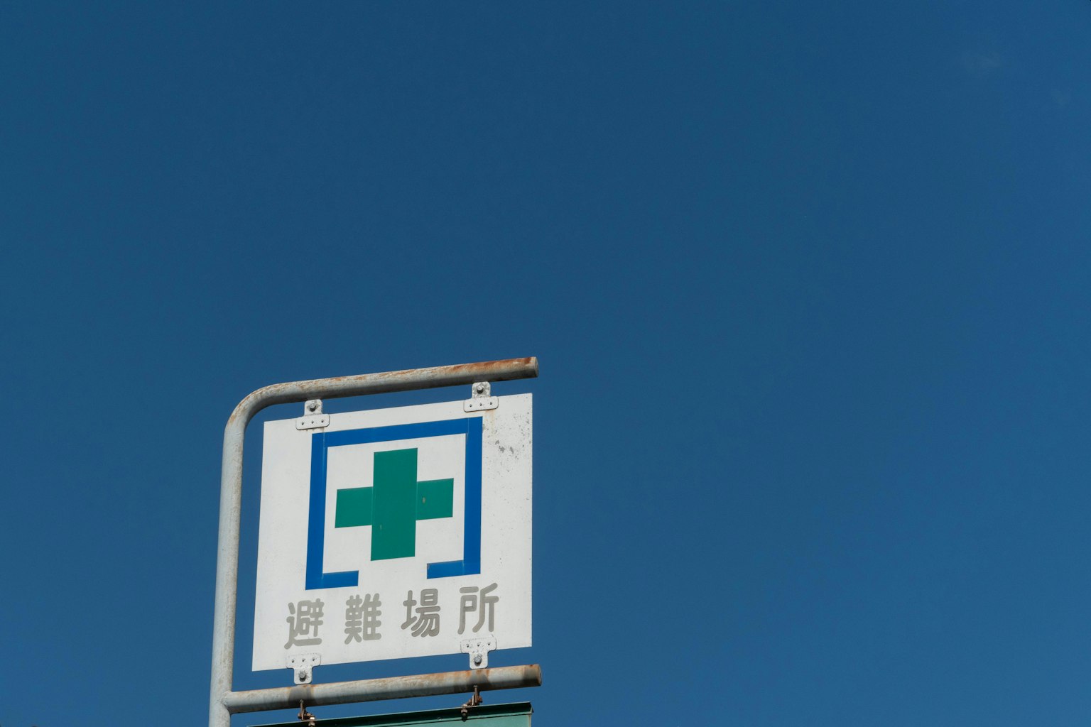 Cartel de farmacia con una cruz verde contra un cielo azul