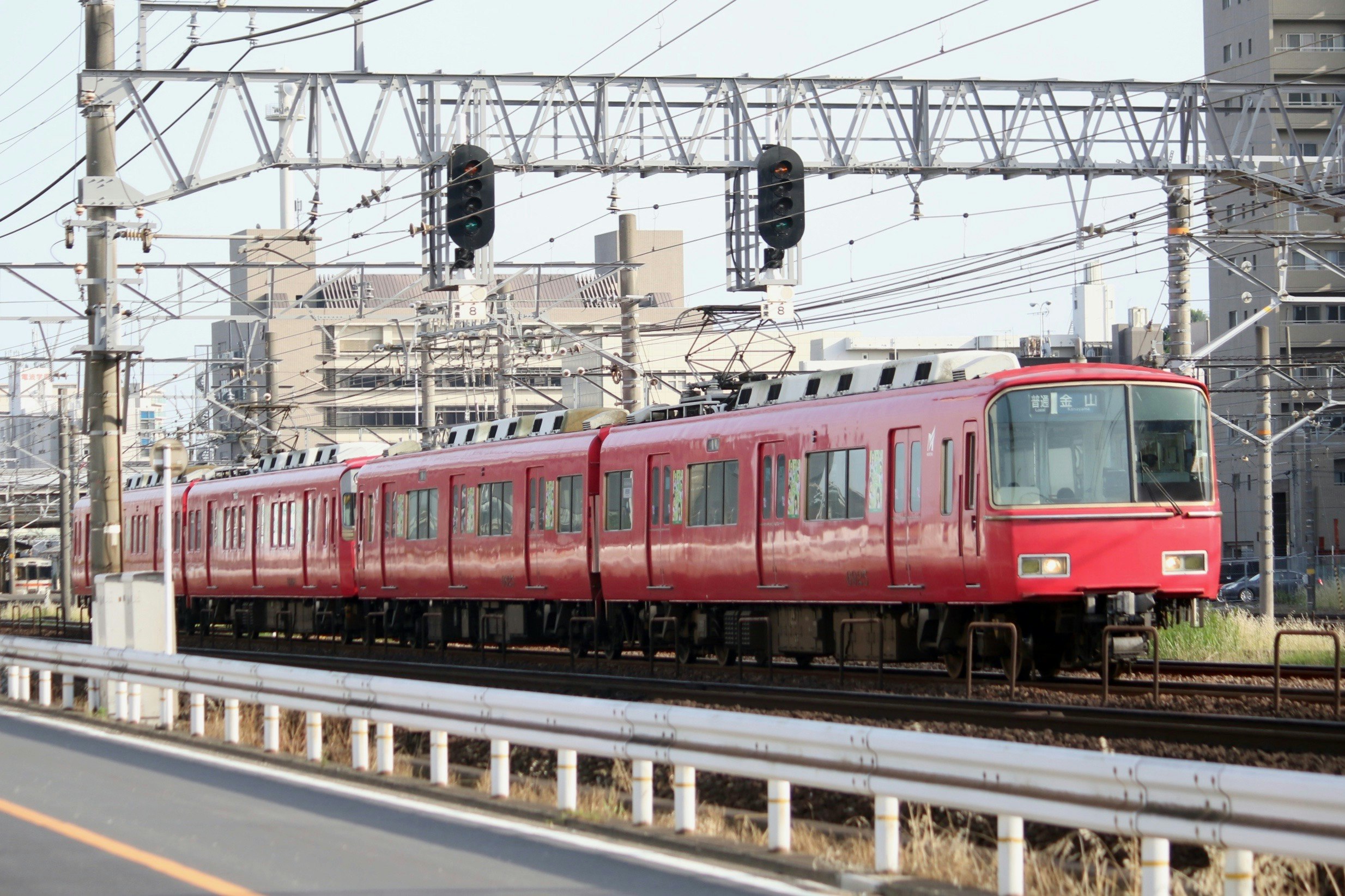 赤い電車が高架の線路を走る駅前の風景