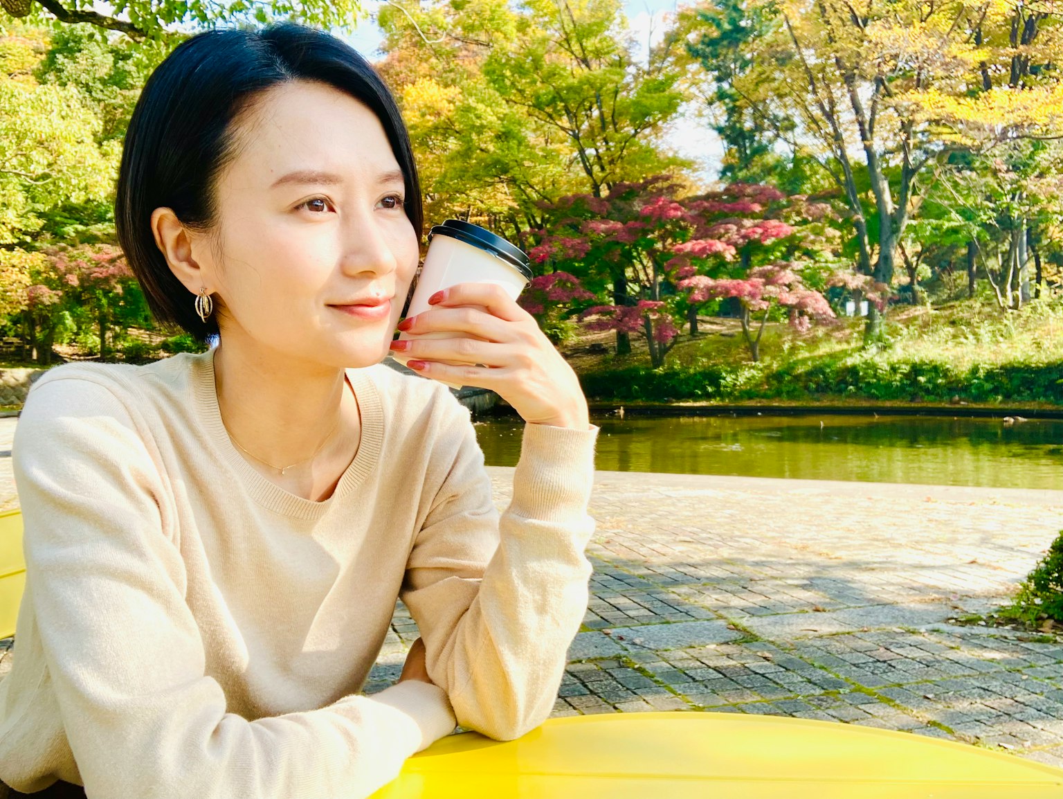 公園中喝咖啡的女性肖像，面帶寧靜表情，自然背景