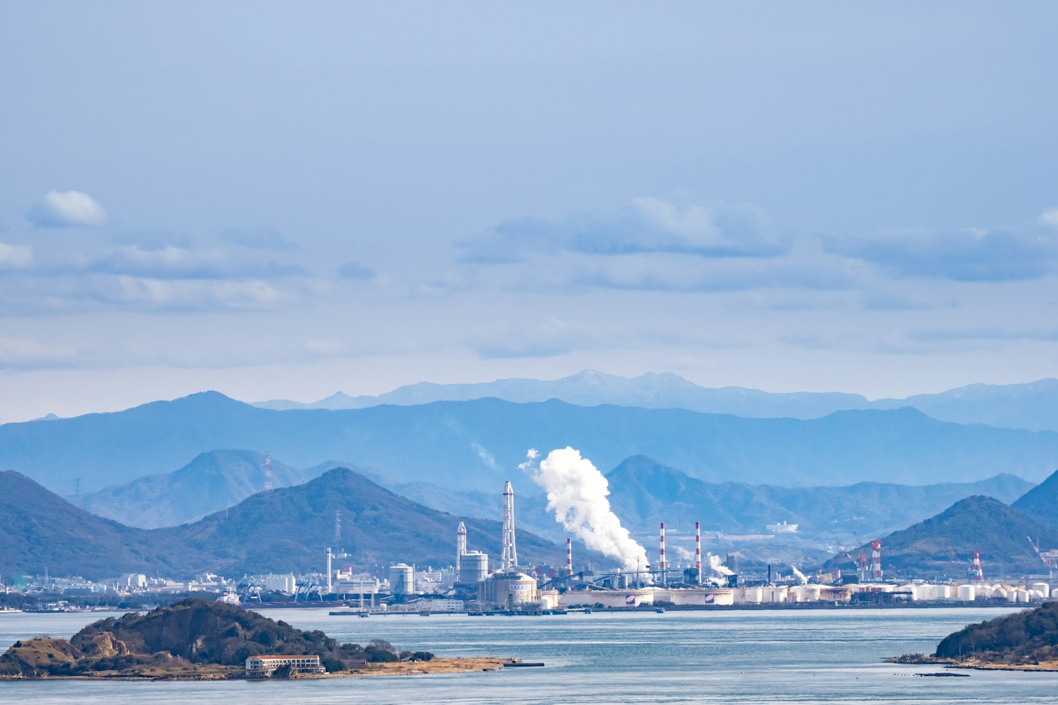 Industrielandschaft mit Fabrikrauch und Bergen