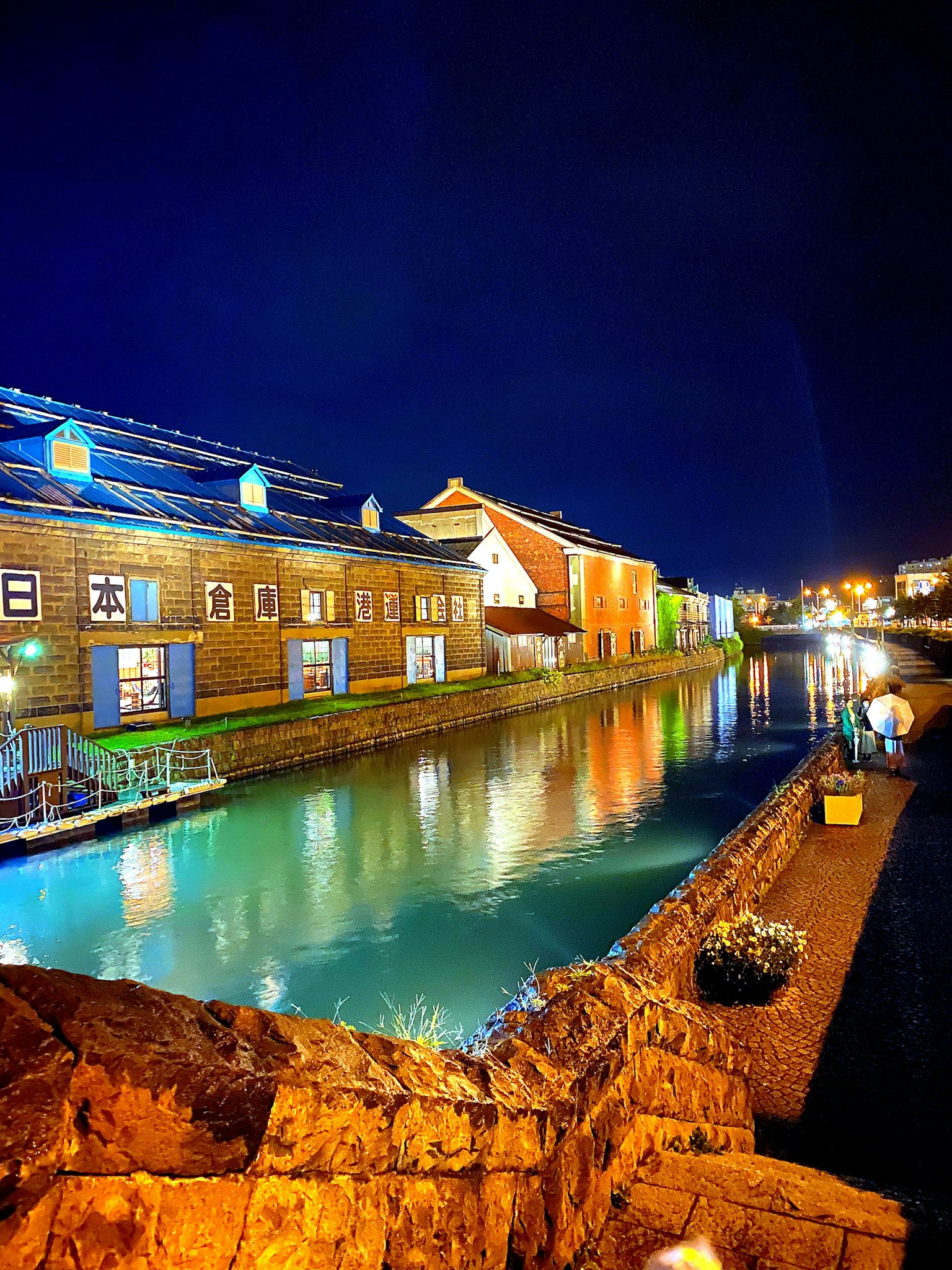 ทิวทัศน์ที่สวยงามของคลองที่เงียบสงบในตอนกลางคืนพร้อมอาคารไม้ที่มีแสงไฟ