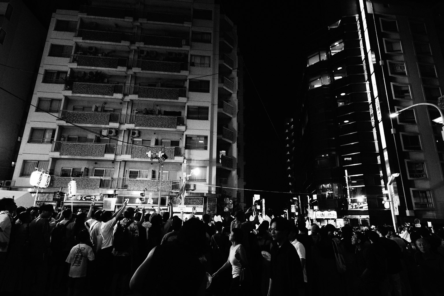 Đám đông tụ tập trong cảnh quan thành phố vào ban đêm với các tòa nhà