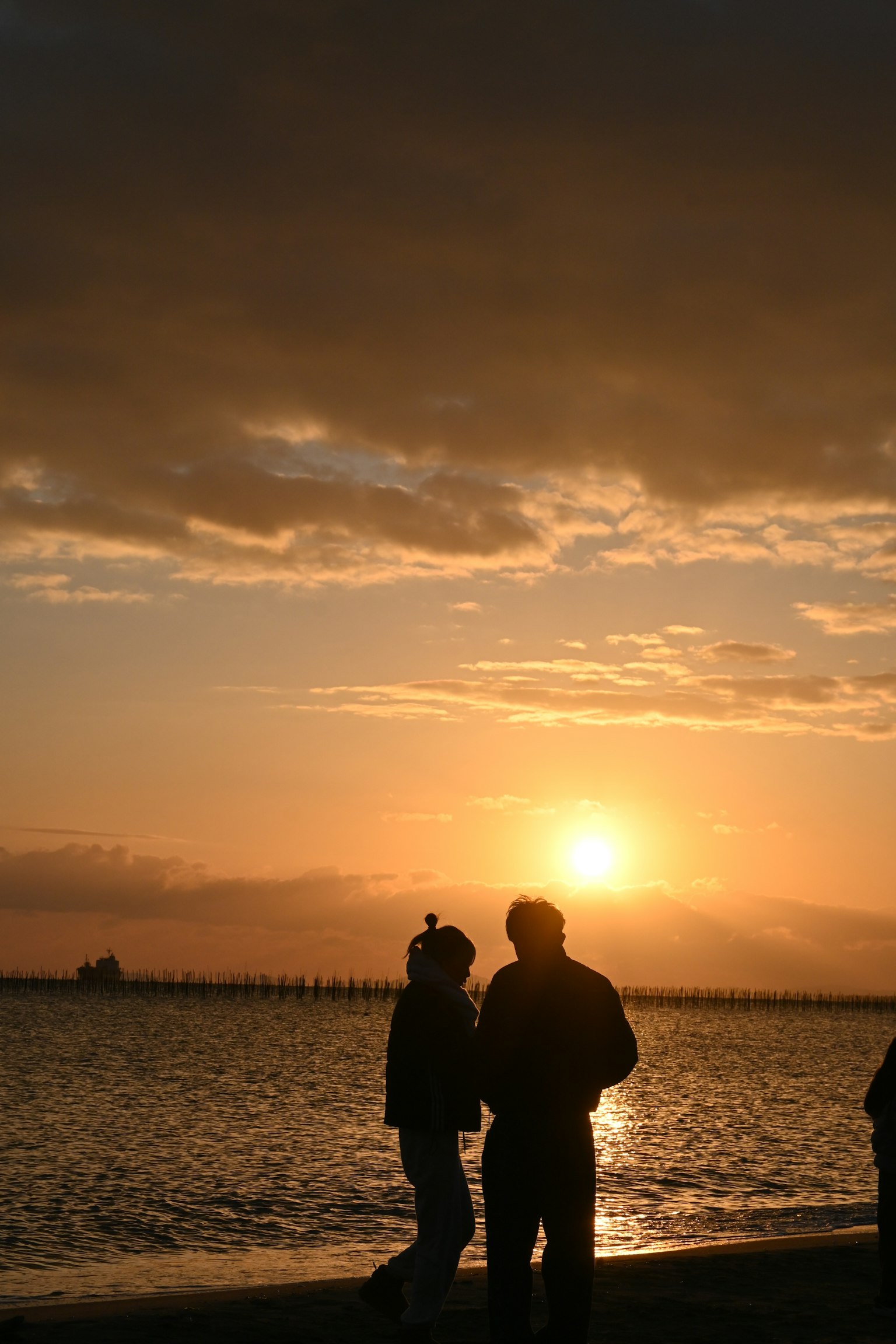 Un couple s'enlaçant sur la plage avec un coucher de soleil en arrière-plan