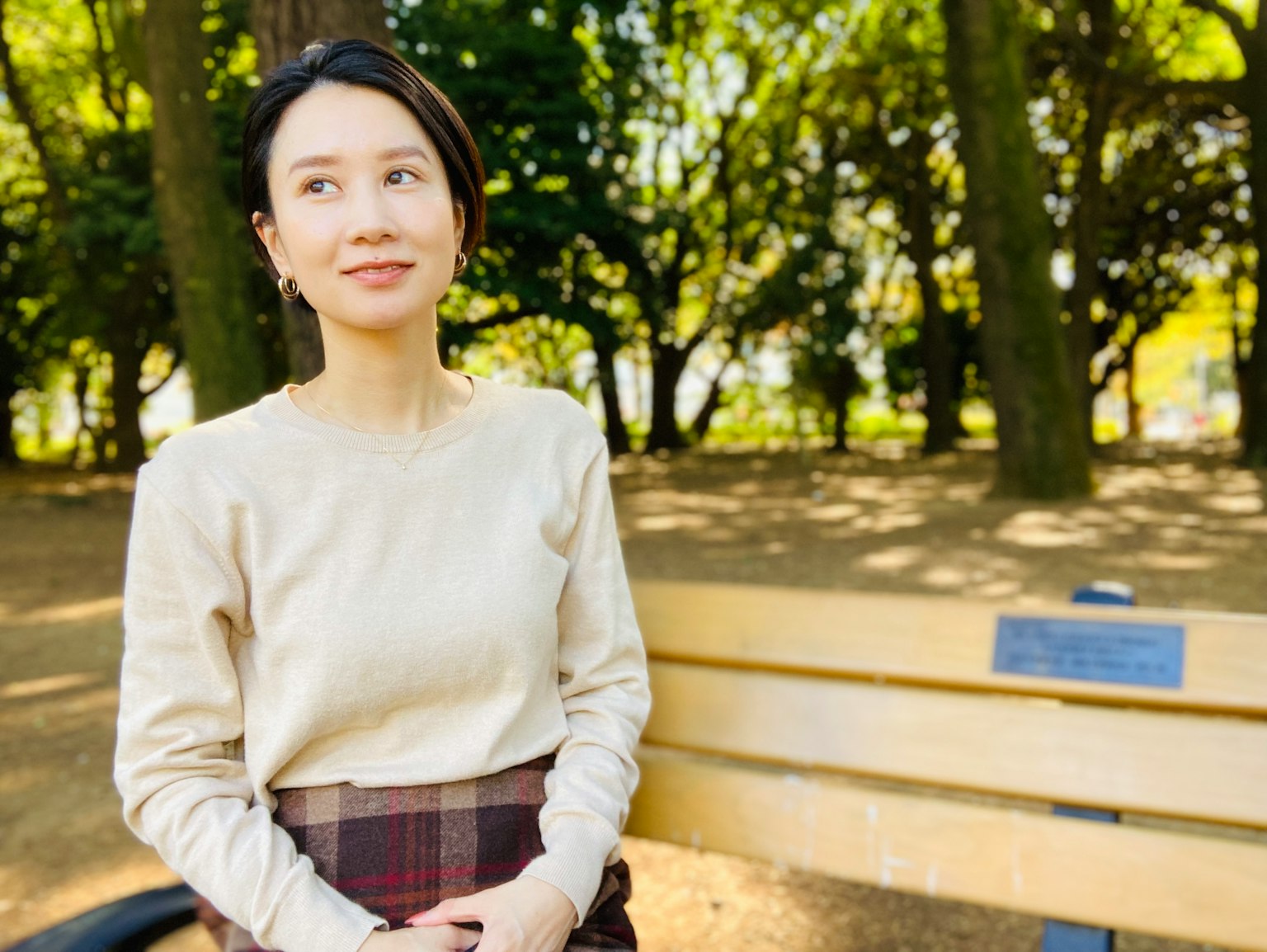 공원 벤치에 앉아 있는 여성의 초상, 배경에는 녹색 나무와 평온한 표정