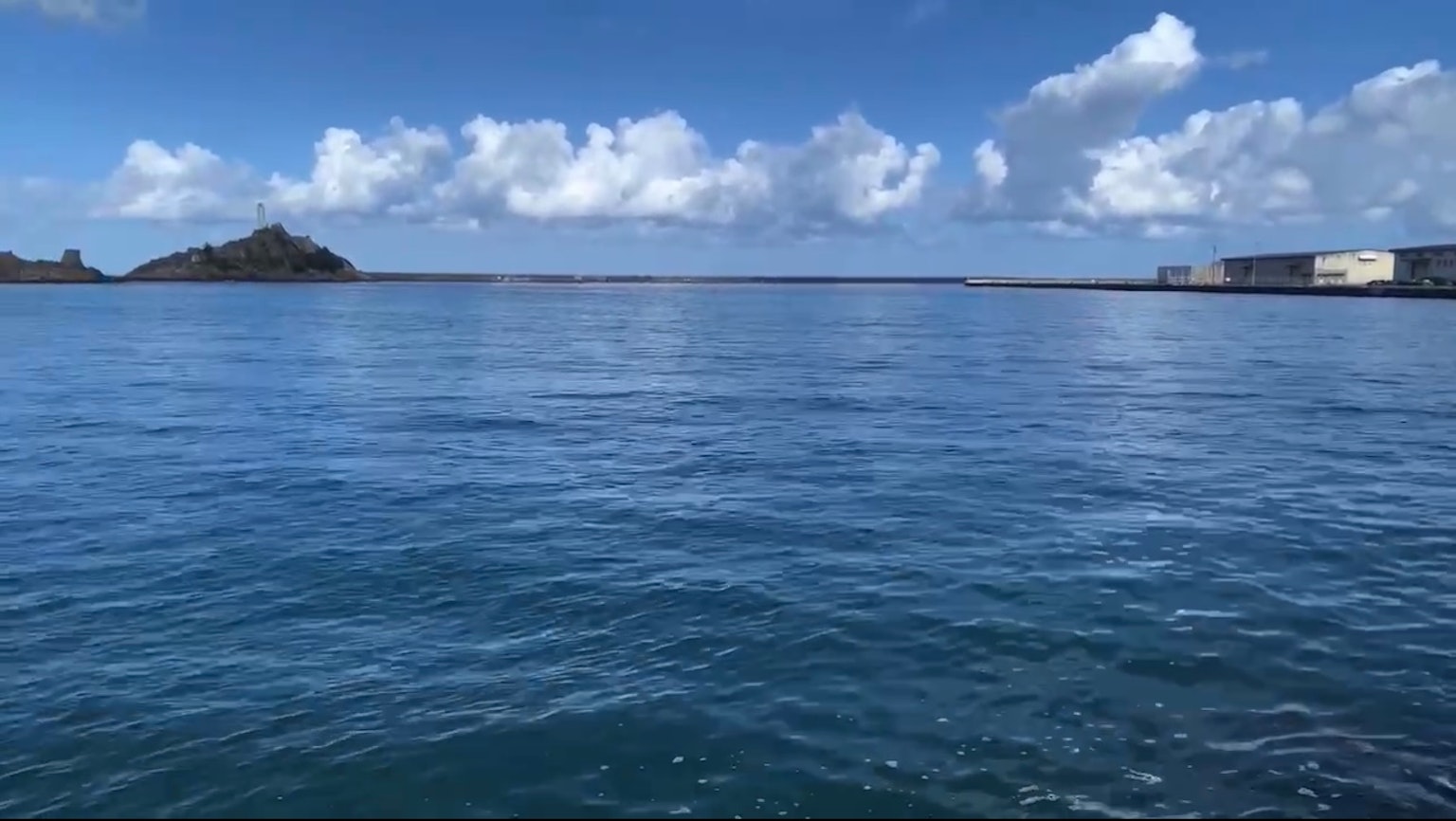 ทะเลสงบและท้องฟ้าสีฟ้าพร้อมวิวเกาะและท่าเรือ