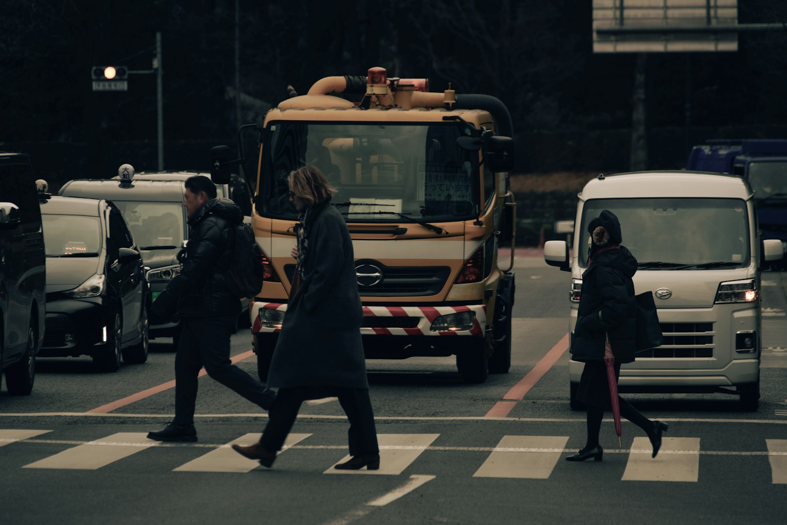 Pedoni che attraversano un attraversamento pedonale con un camion giallo sullo sfondo