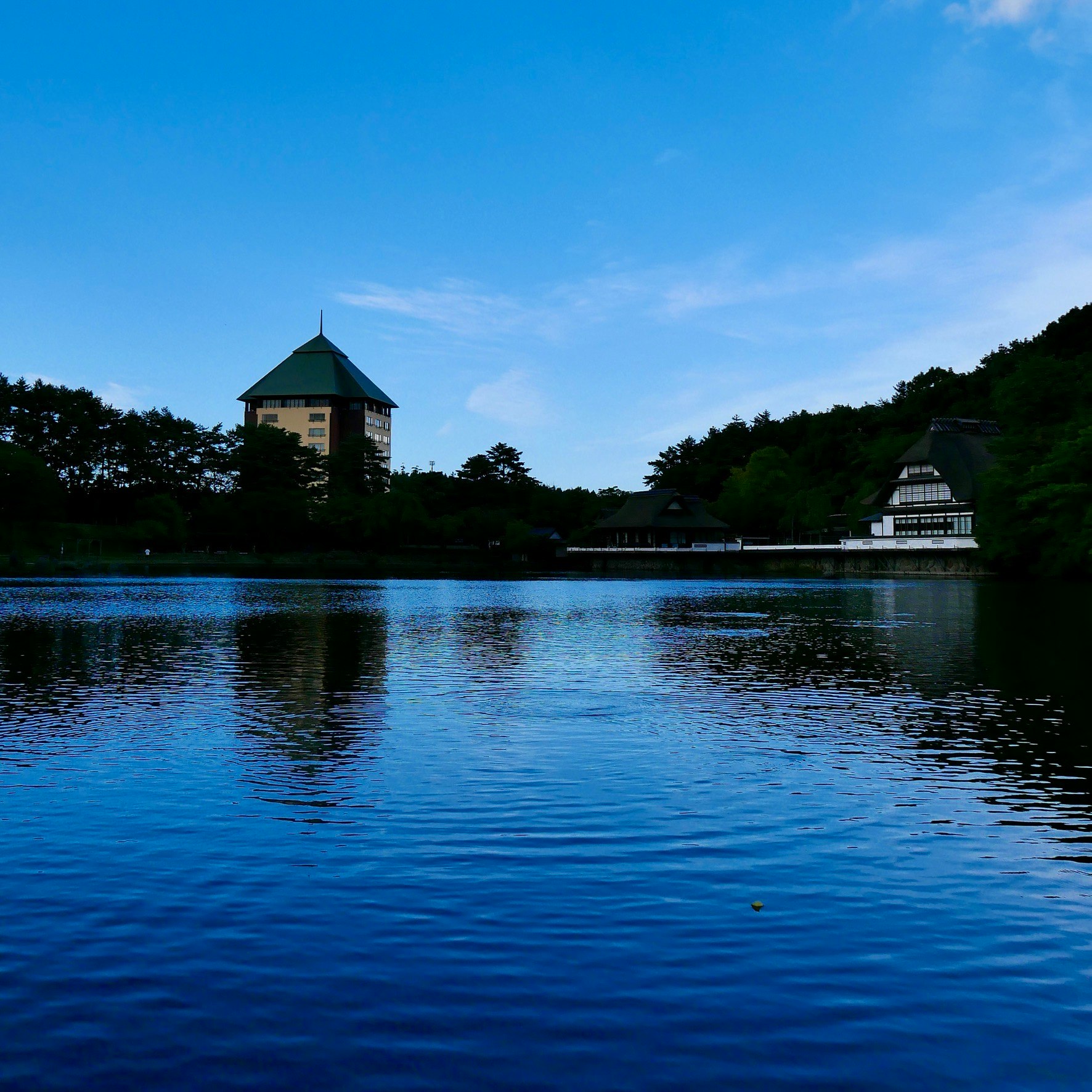 青い水面に映る湖畔の塔と建物の風景