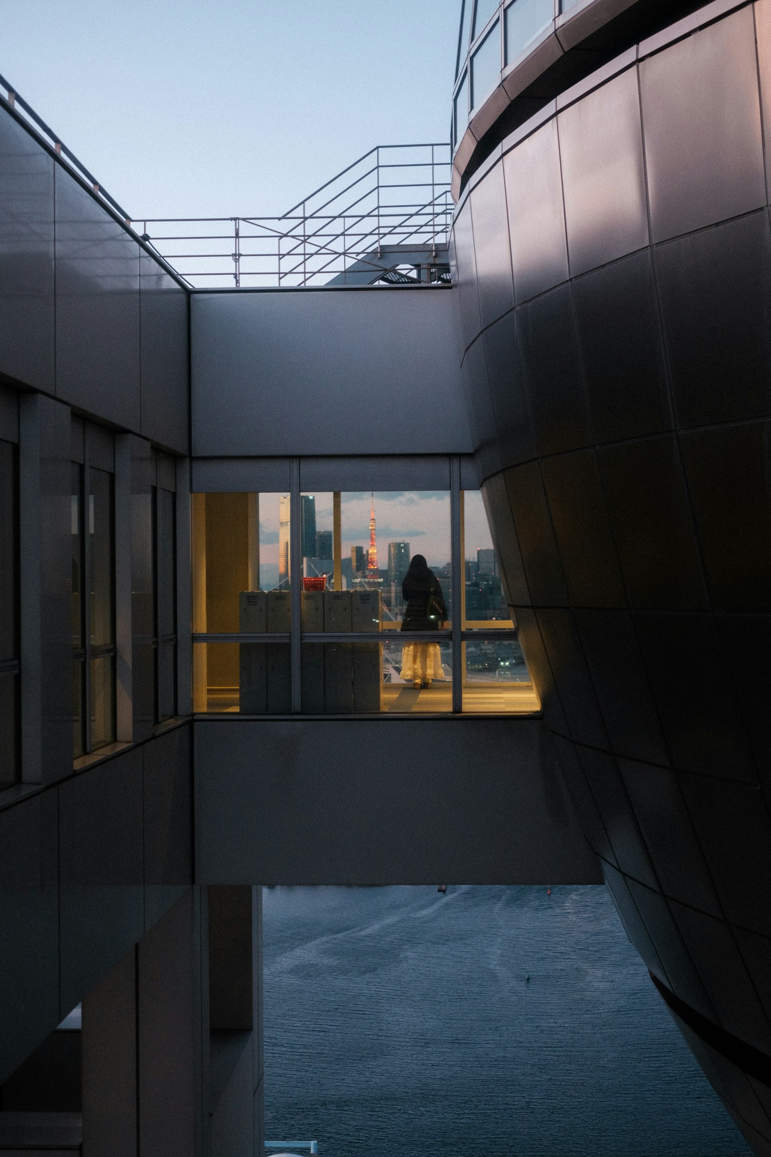 Persona in piedi dietro un muro di vetro tra edifici con vista sulla città
