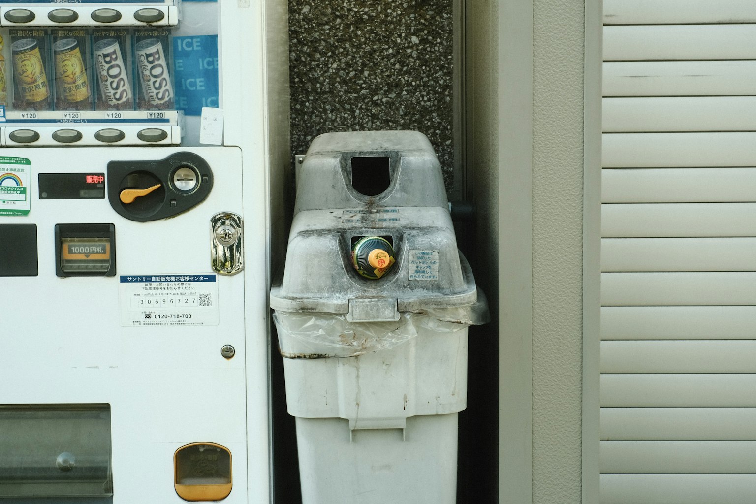 Cestino sporco accanto a un distributore automatico con una bottiglia arancione