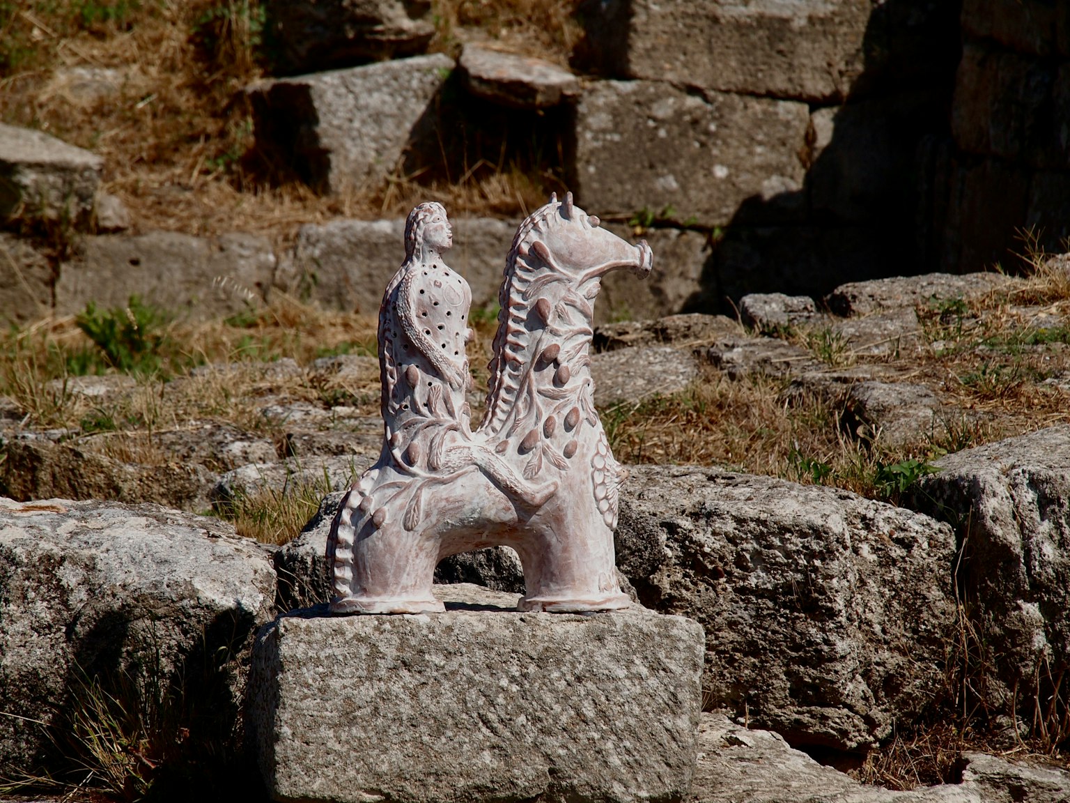 Antike Skulptur einer Figur, die auf einem Pferd steht, auf einem Stein