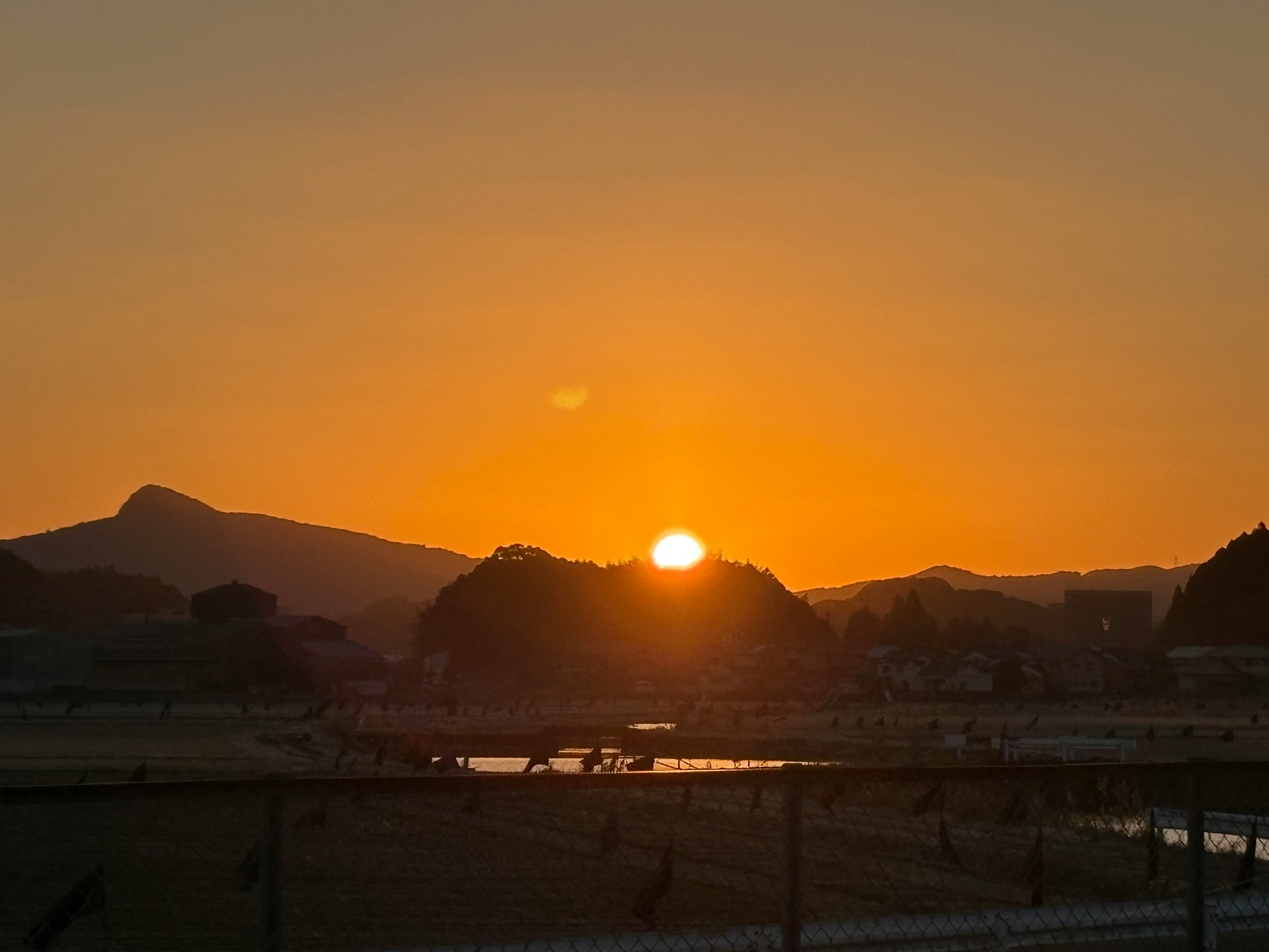 夕日に照らされる山並みと川沿いの風景