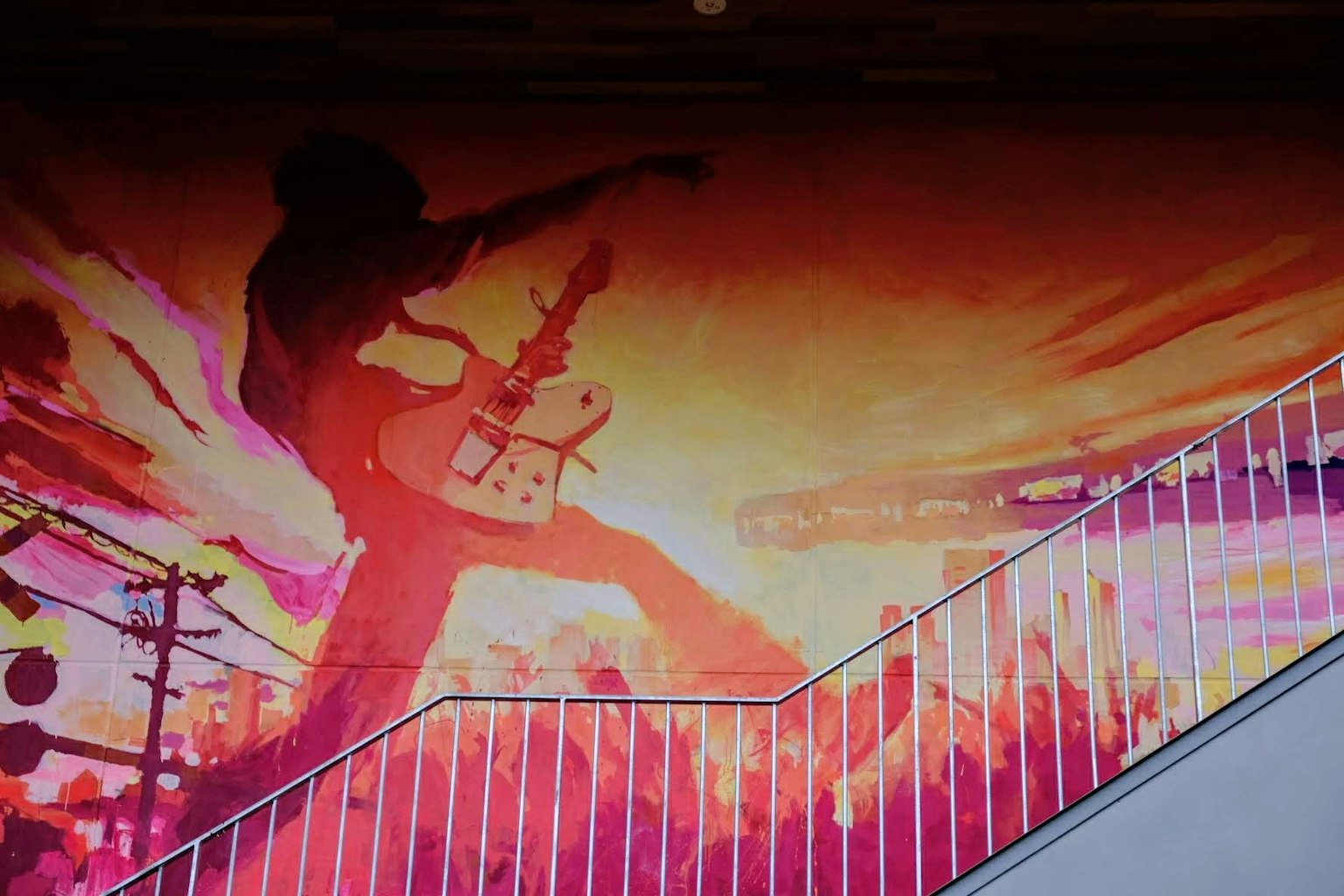 Silhouette énergique d'un guitariste sur une fresque vibrante avec un fond coloré