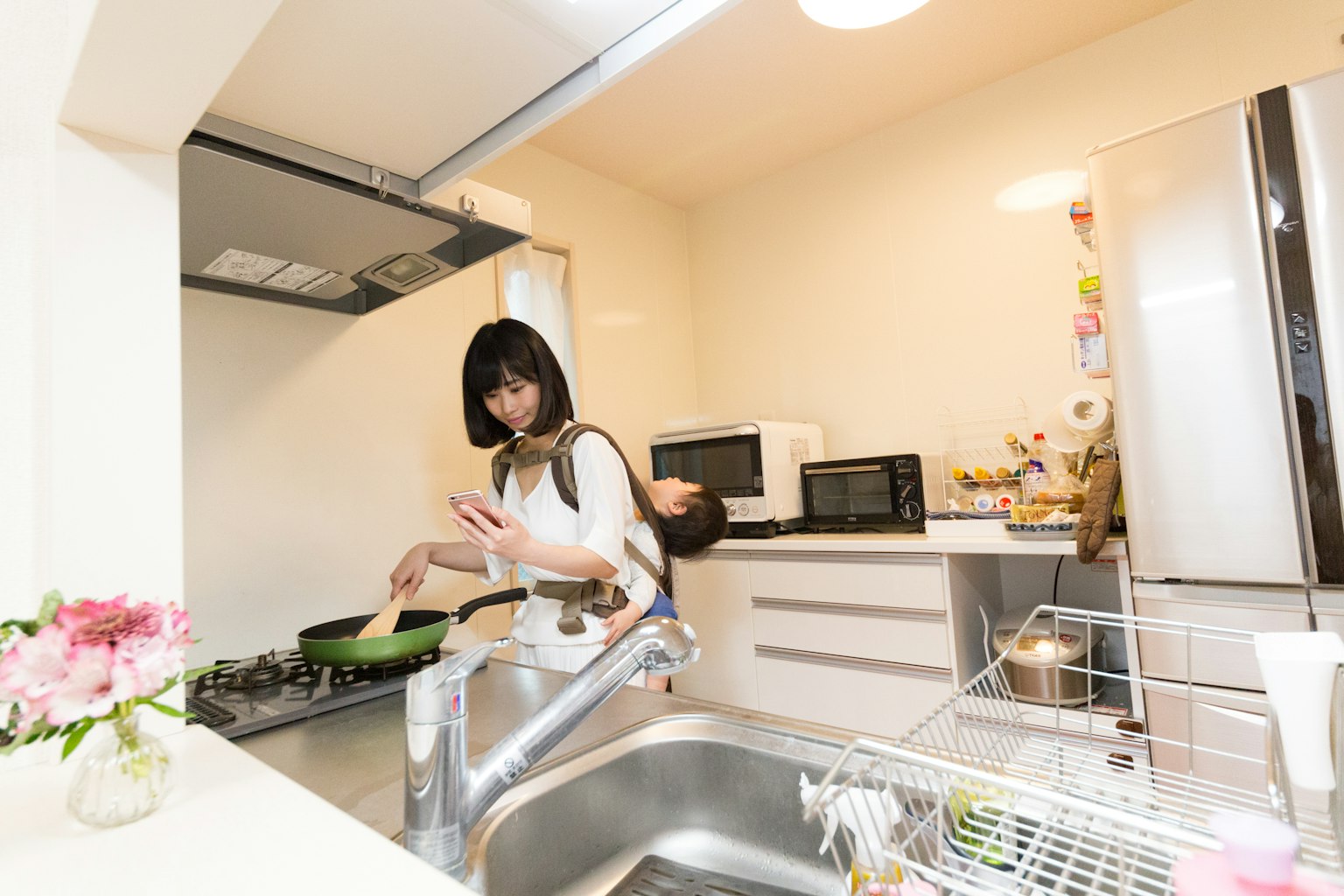 Una mujer cocinando en una cocina brillante con un bebé