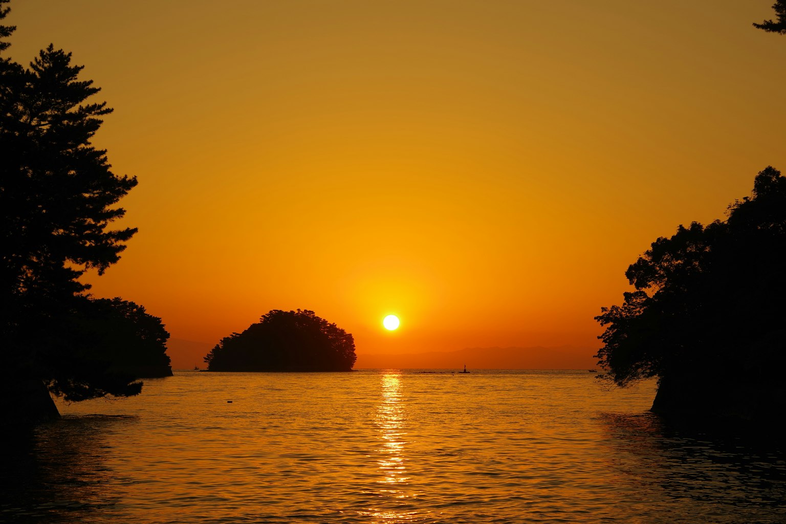 Schöne Landschaft des Sonnenuntergangs über dem Meer mit ruhigem Wasser und silhouettierten Inseln