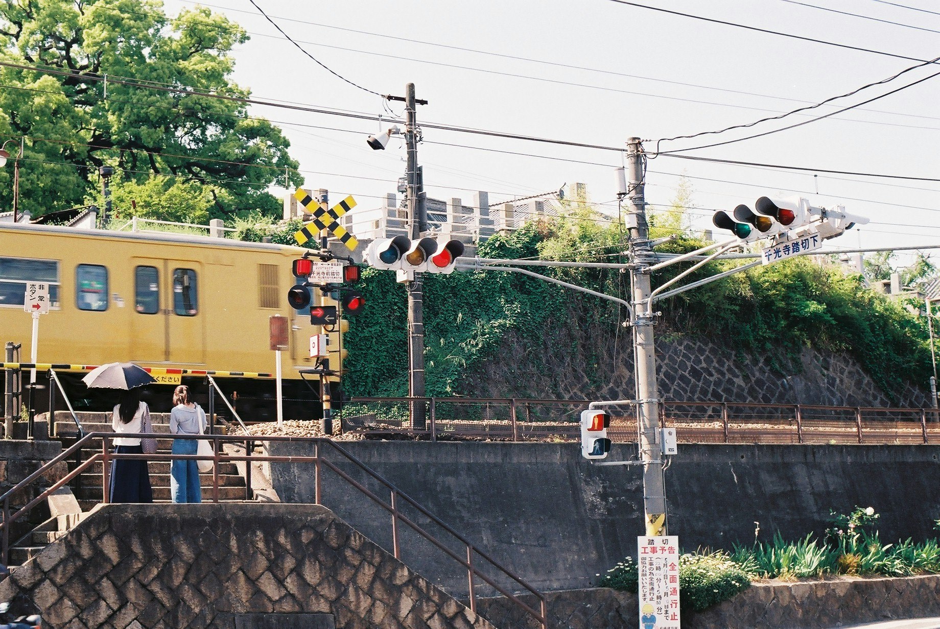 踏切の信号機と線路を走る列車のある風景