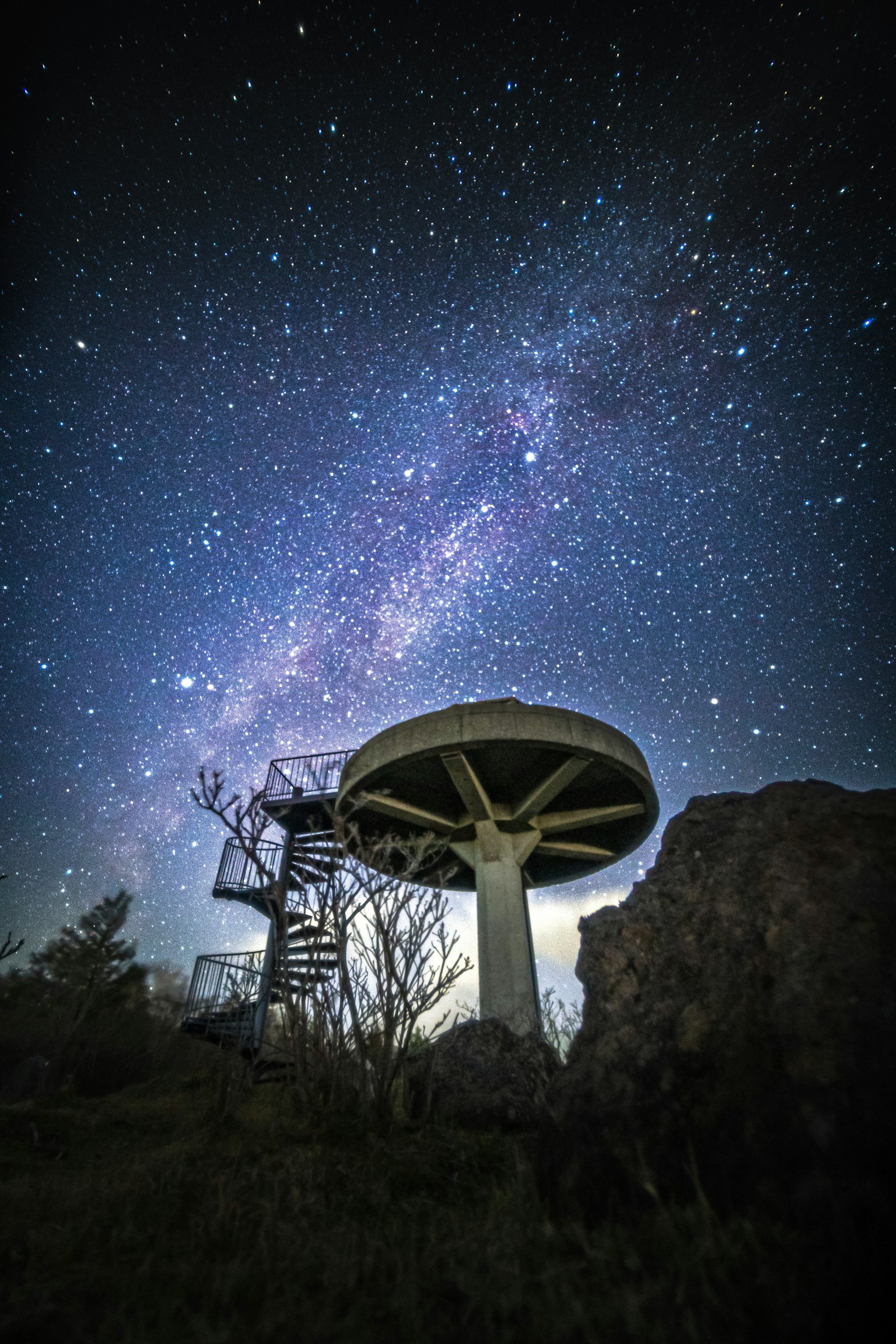 Silhouette of a circular structure and stairs under a starry sky