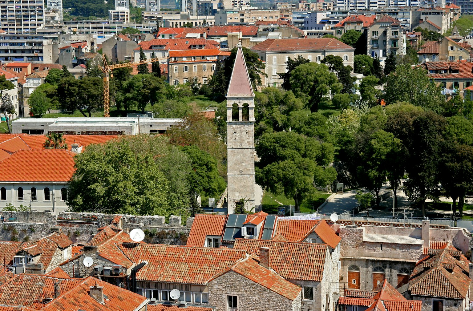 Stadtansicht mit roten Ziegeldächern und einem Steinglockenturm
