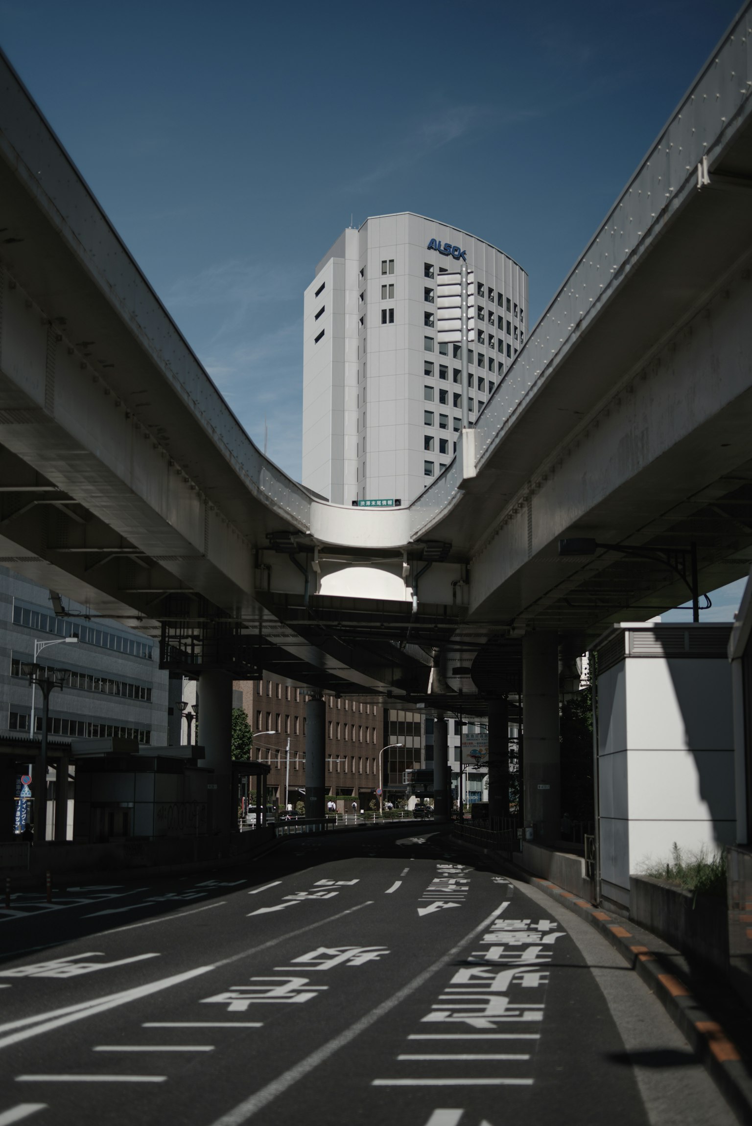 Urban scene under elevated roadway featuring a tall building in the background