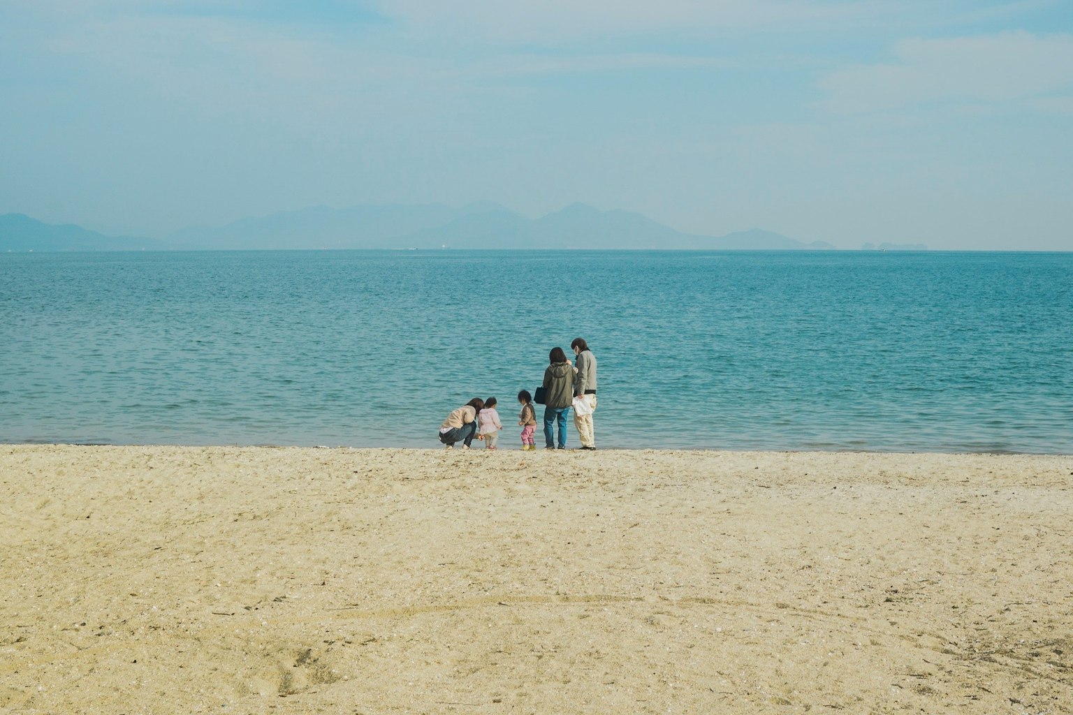 Famiglia in piedi sulla spiaggia che guarda il mare