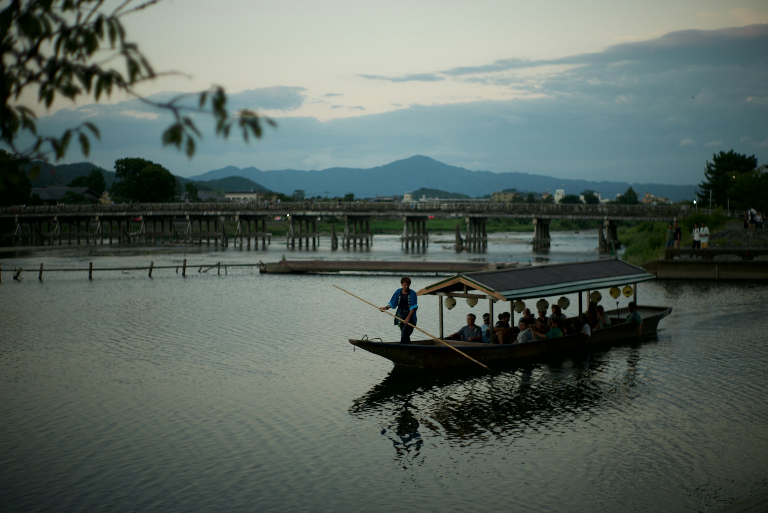 宁静河流中人们在船上的景色 背景有桥和山