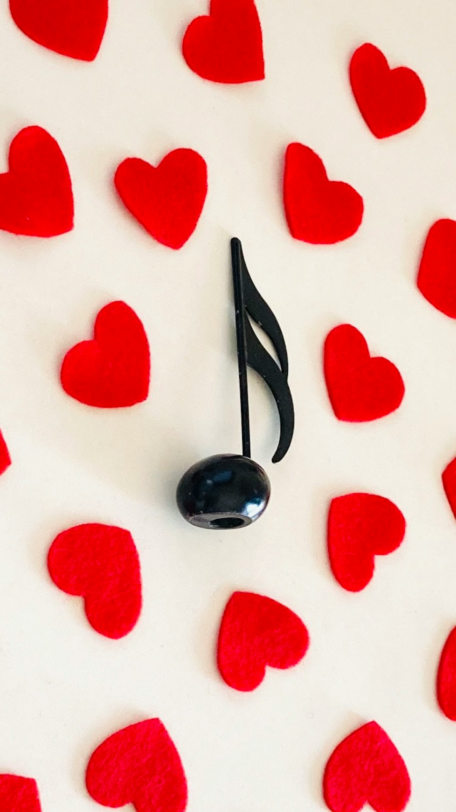 Una nota musical negra rodeada de corazones rojos