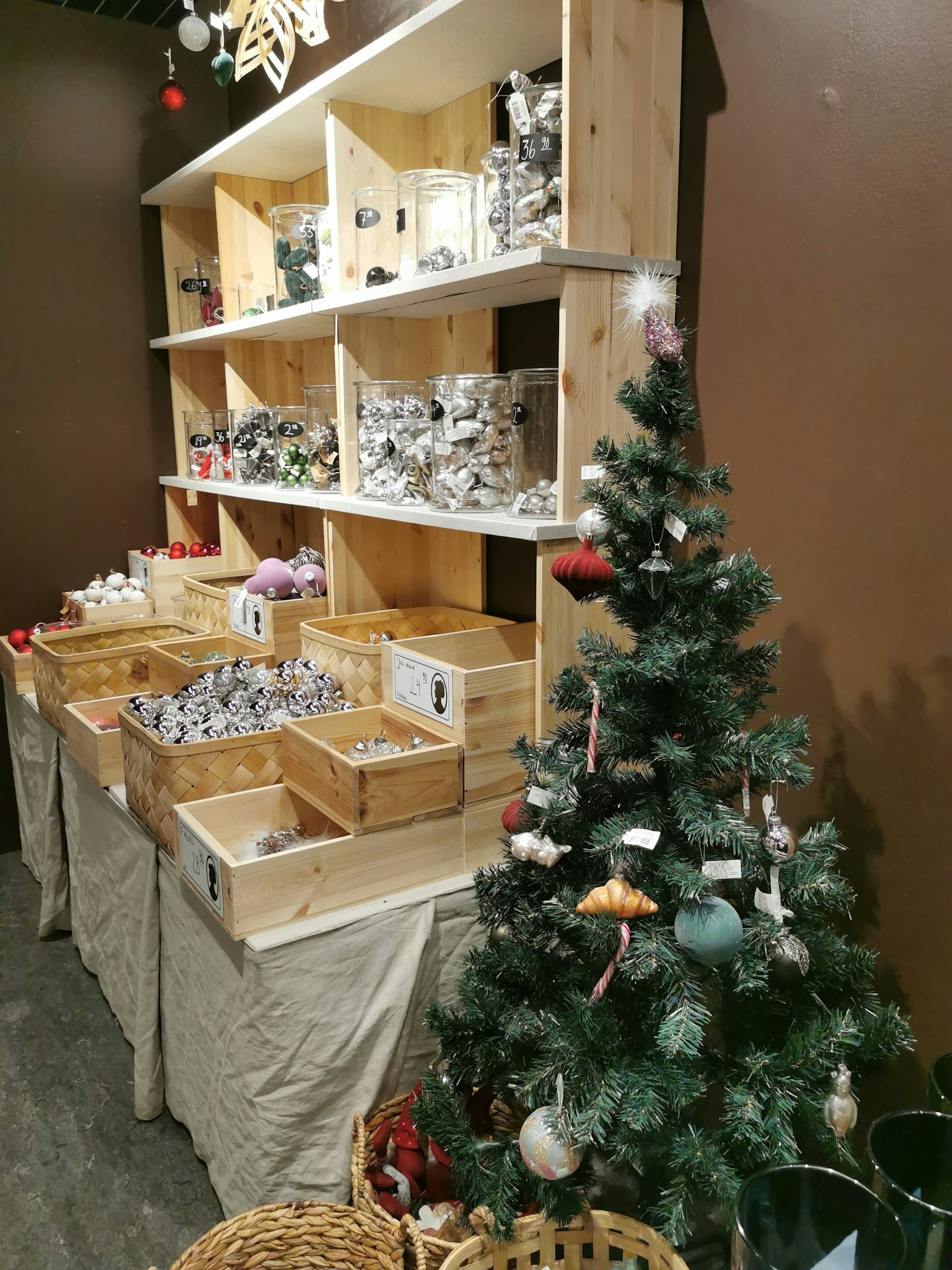 Estantes de madera llenos de artículos decorativos y un pequeño árbol de Navidad