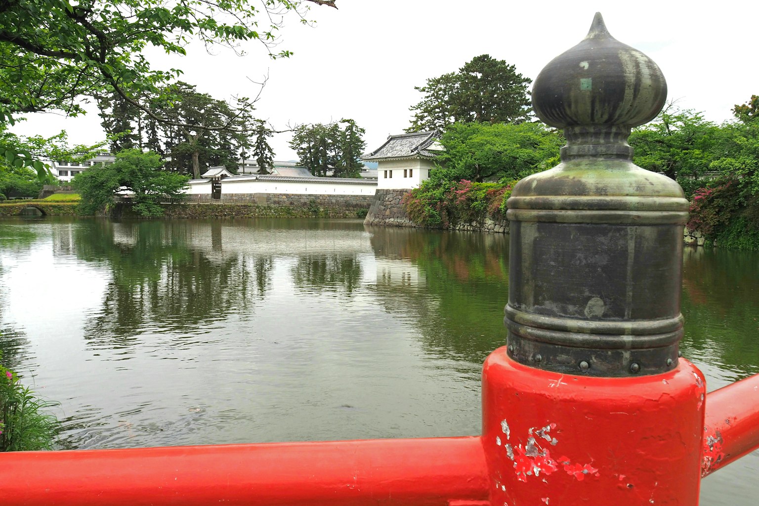 Pemandangan kastil Jepang dengan pegangan jembatan merah dan kolam