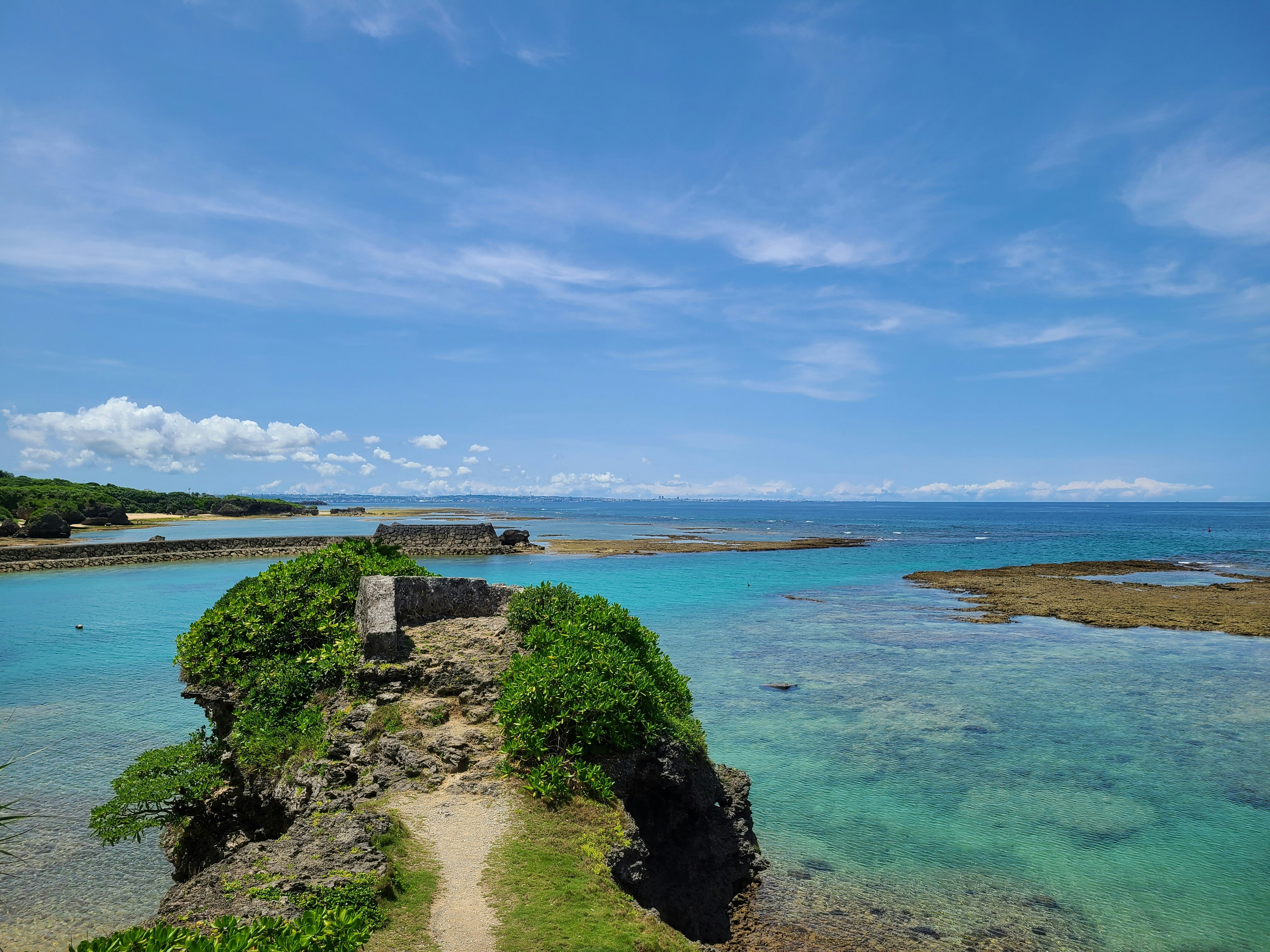 翡翠色海水與岩石小岬，晴朗藍天海岸風景
