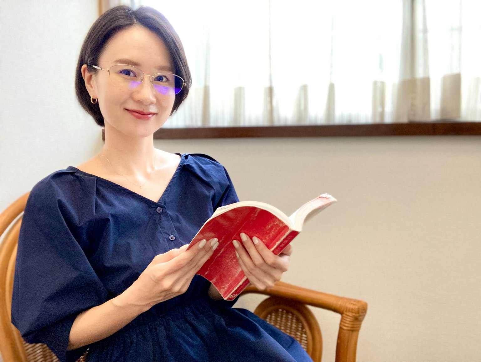 坐在椅子上拿著書的女性肖像明亮的室內環境，窗戶透入自然光