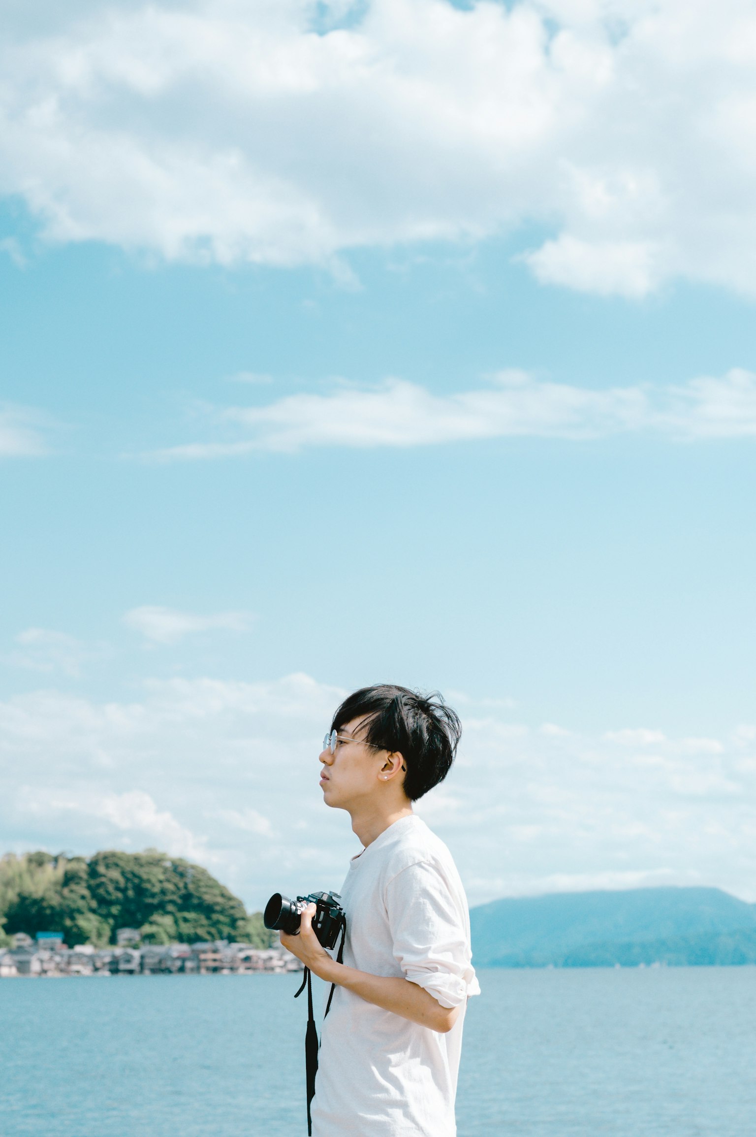 ชายหนุ่มถือกล้องใต้ท้องฟ้าสีฟ้า