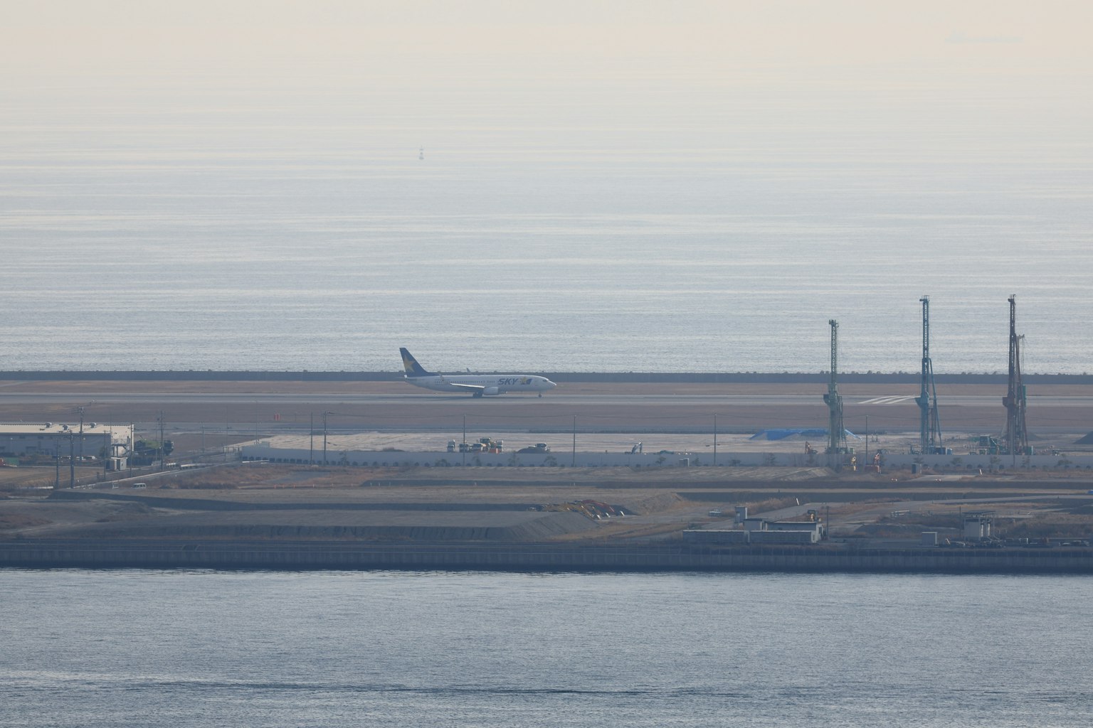 Un avion atterrissant à un aéroport avec des cheminées en arrière-plan