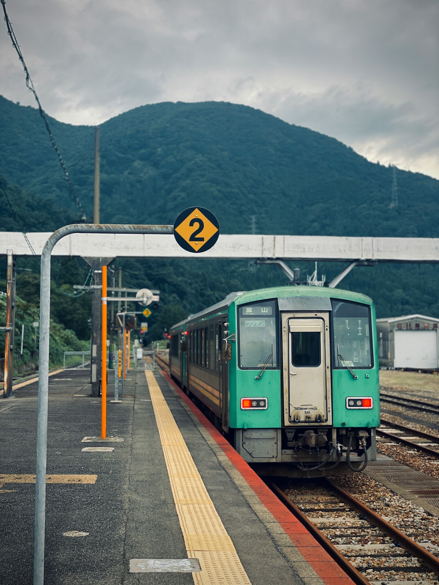 緑色の列車が駅に停車している山の風景