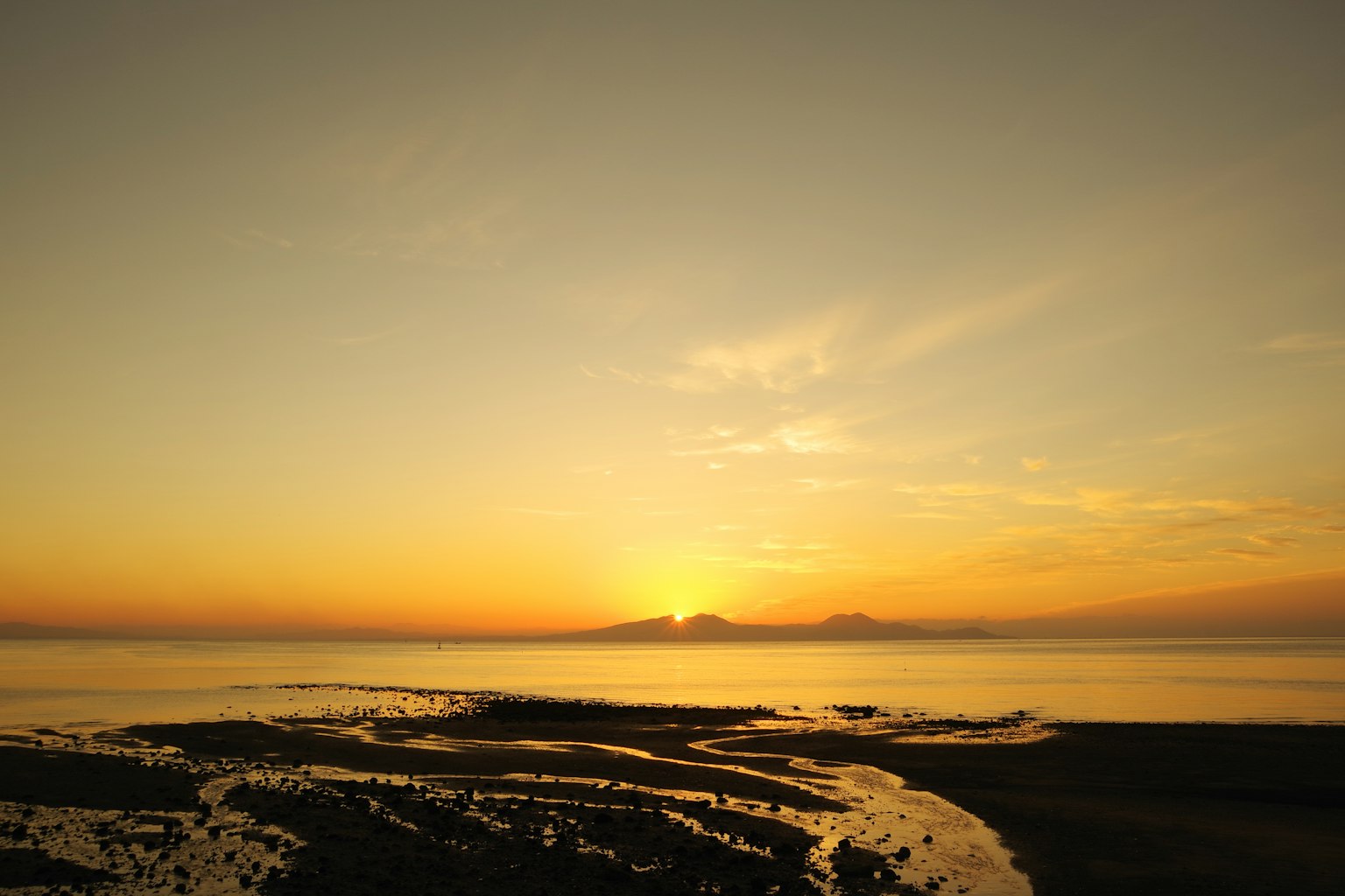 Tramonto sull'oceano con montagne lontane