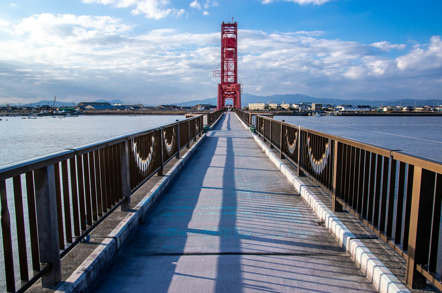 Scenic view of a bridge with a red tower clear blue sky and clouds